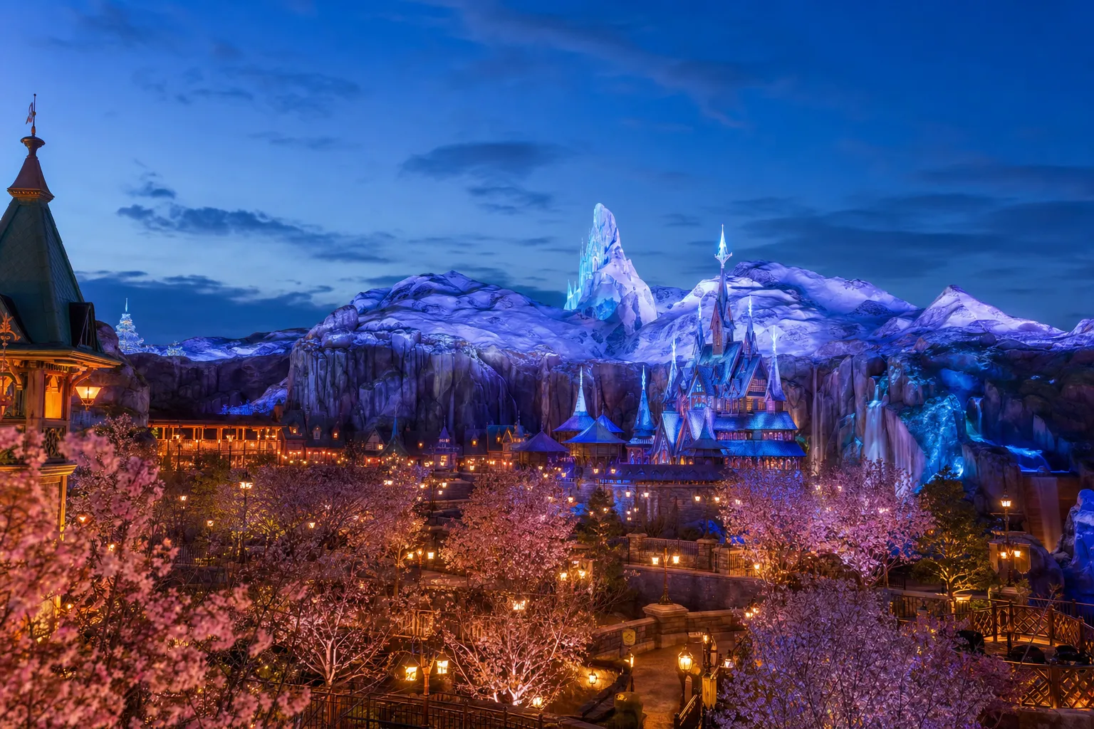 The snow-dusted castle and frozen-fjord facade of Anna and Elsa's Frozen Journey in the Frozen area of Fantasy Springs at Tokyo DisneySea, illuminated at twilight