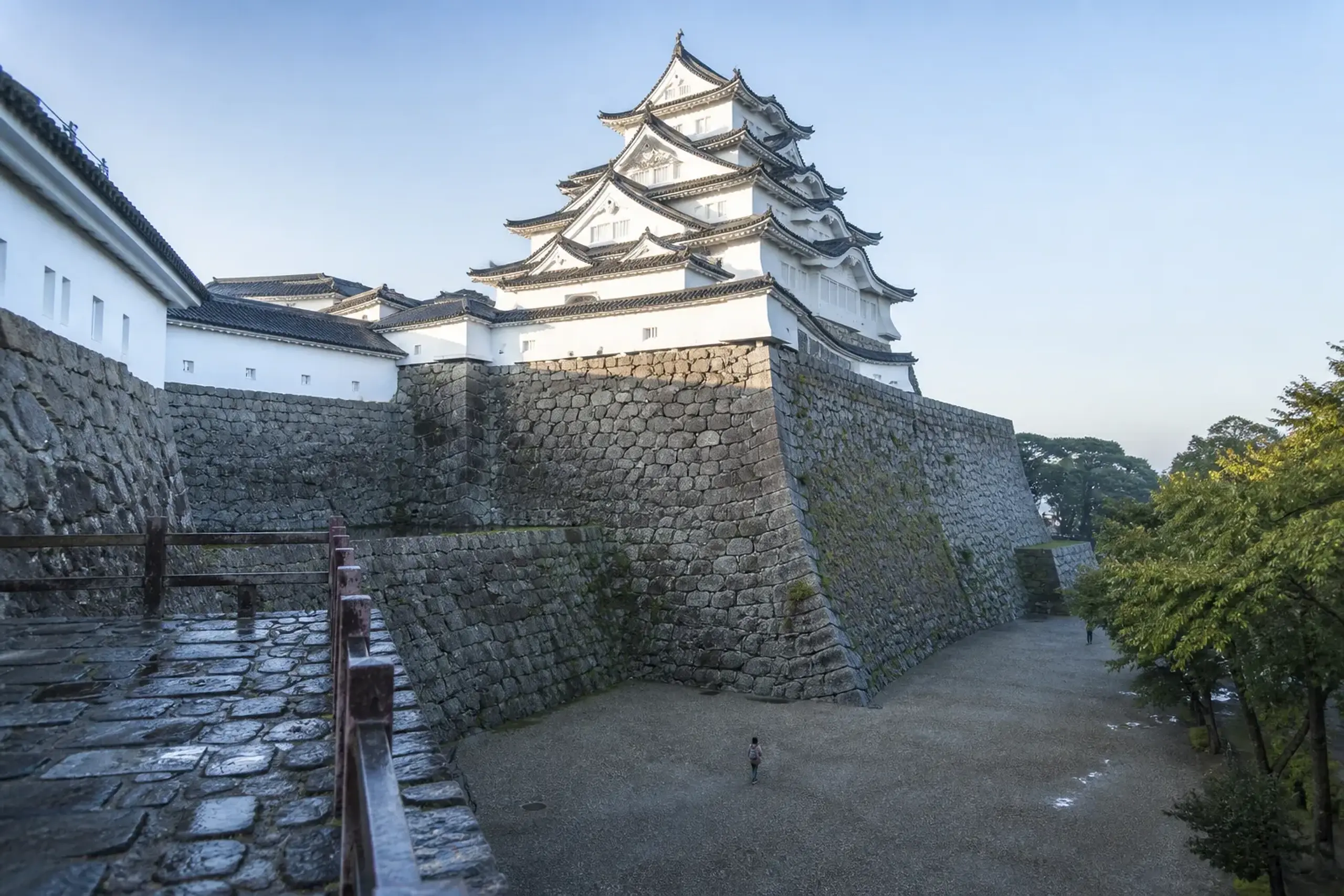 White keep of Himeji Castle rising above stone defensive walls in clear morning light