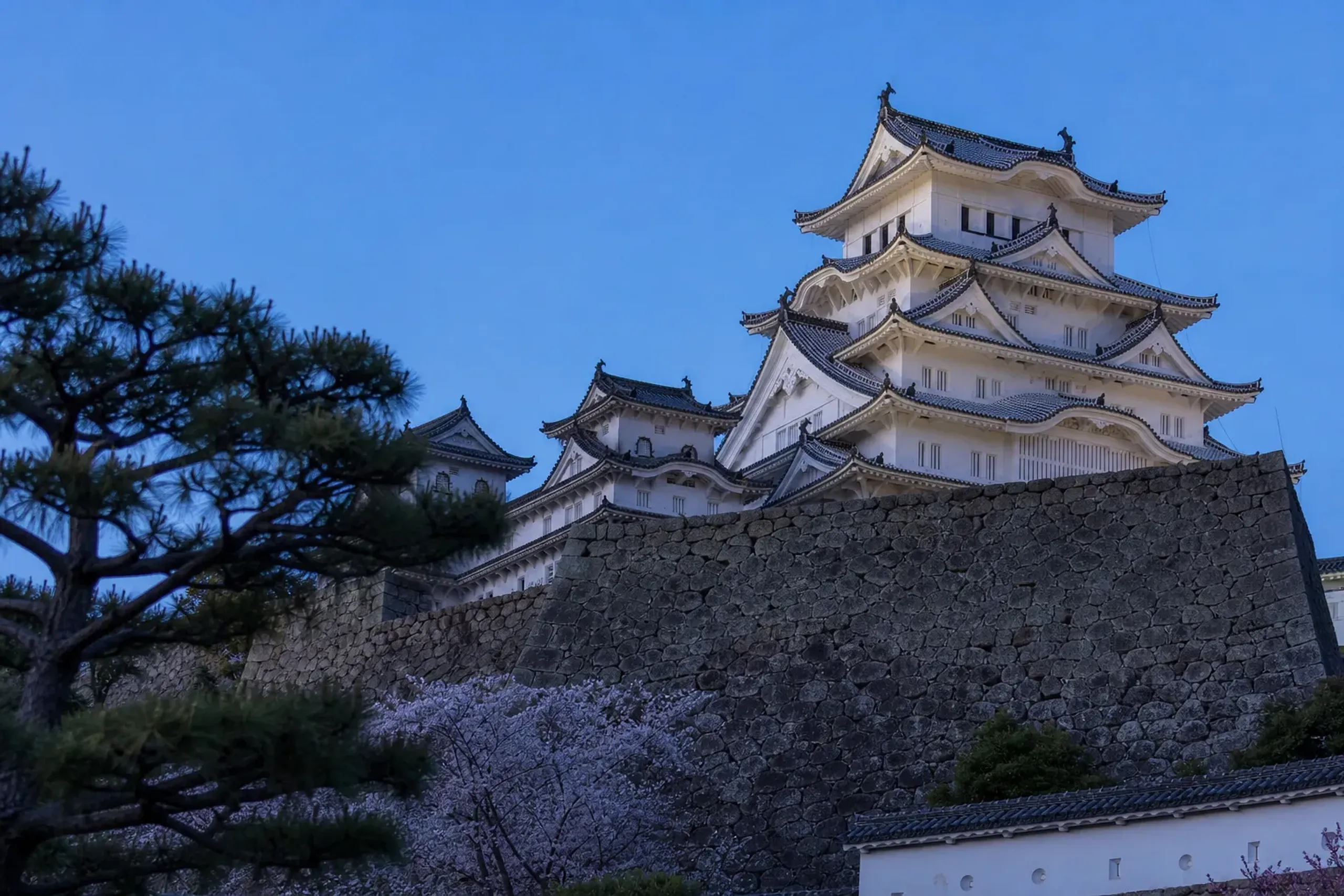 The white plaster keep of Himeji-jō, the White Heron Castle, its multi-tiered roofs poised like a heron about to take flight against a clear sky