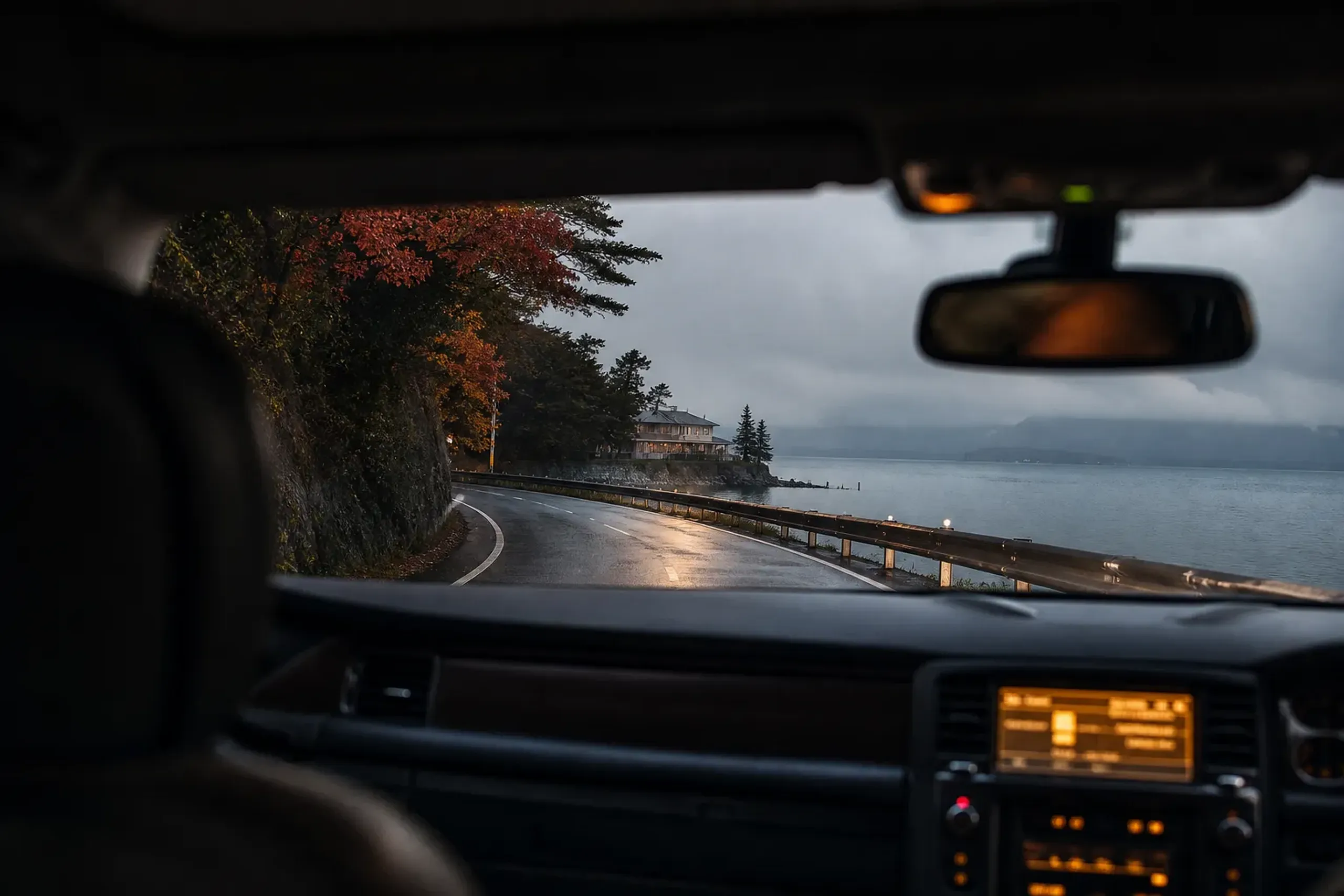 The private car returning along the coastal road toward Yokohama port at dusk, the ship's berth visible ahead in fading evening light