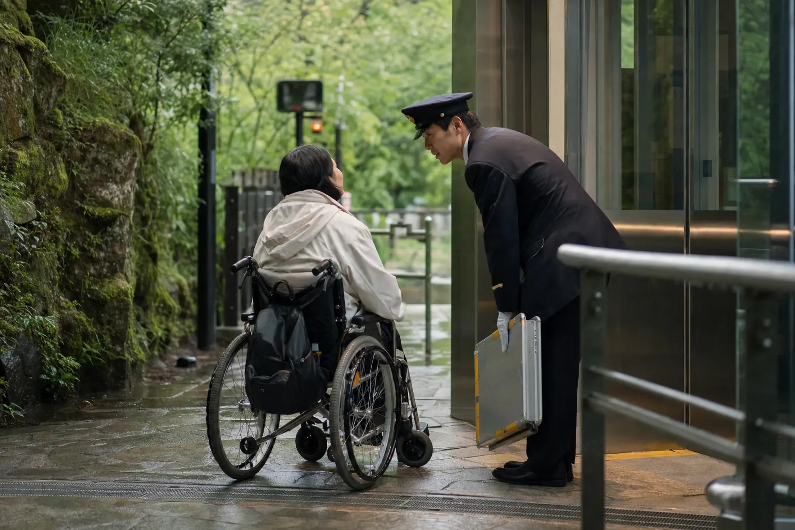 Wheelchair users approach station staff at the ticket gate,