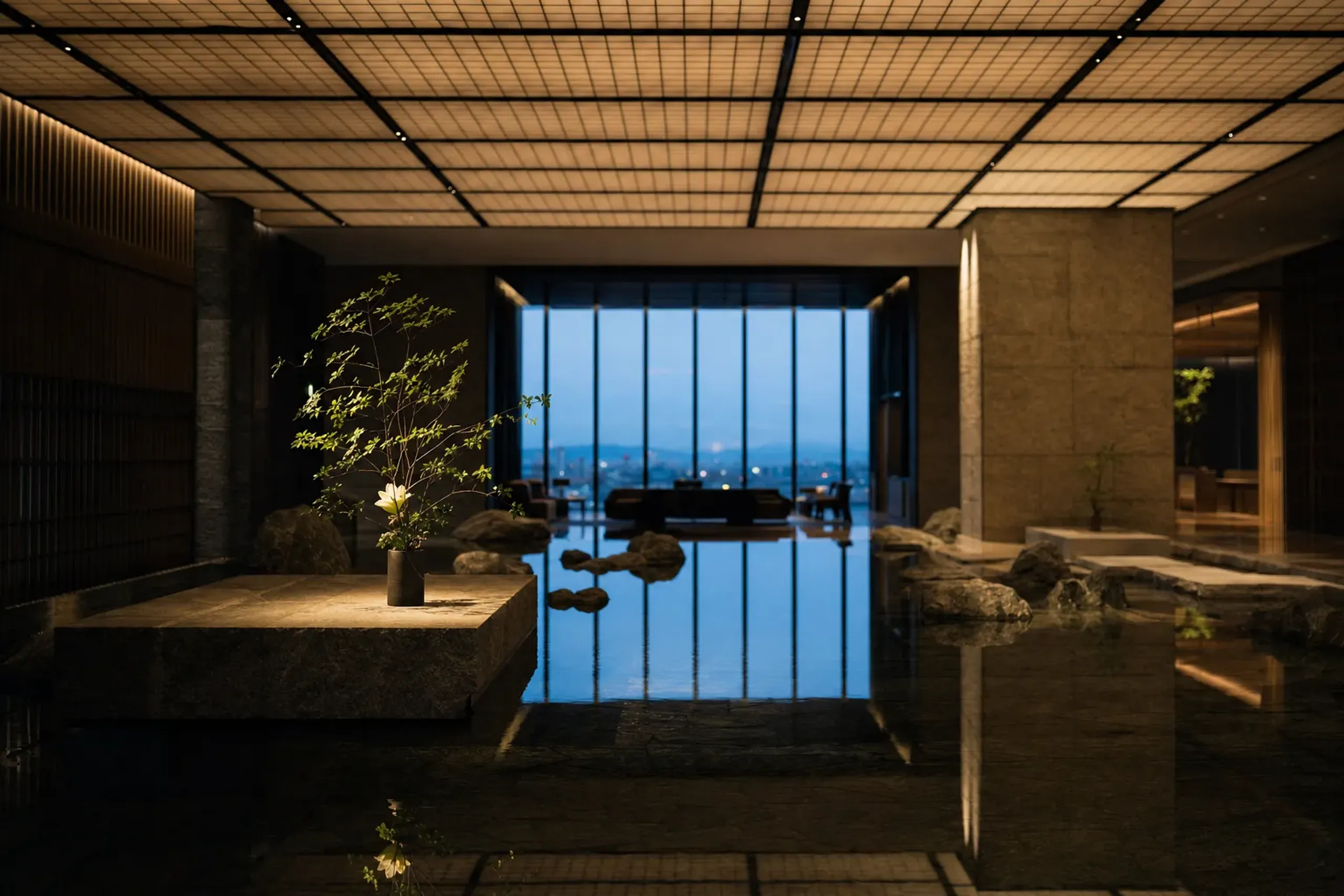 Aman Tokyo 33rd-floor lobby showing the central pond, stone garden, and ikebana within one continuous space