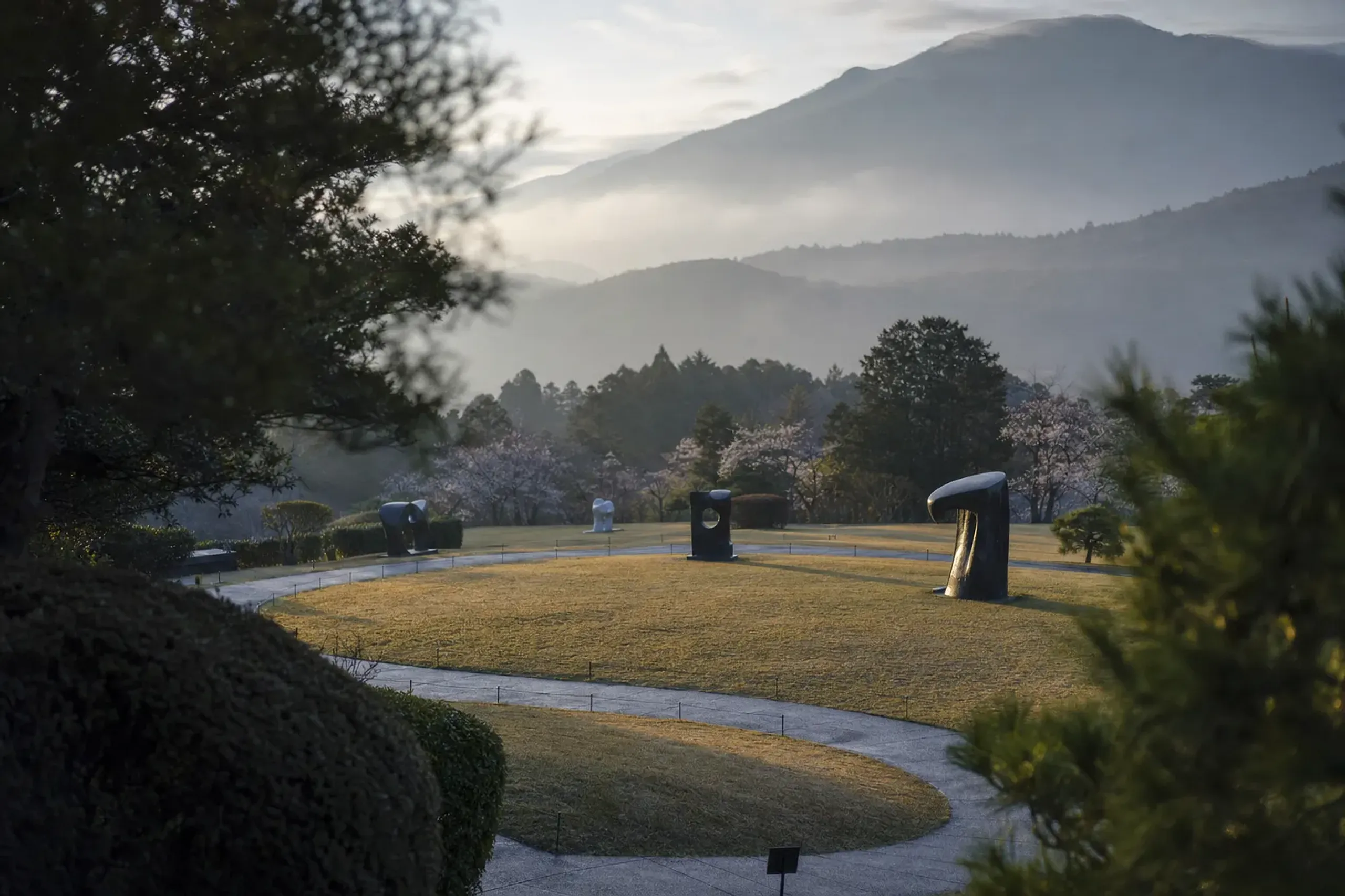Outdoor sculptures at the Hakone Open-Air Museum in morning mist with Hakone mountains in the background