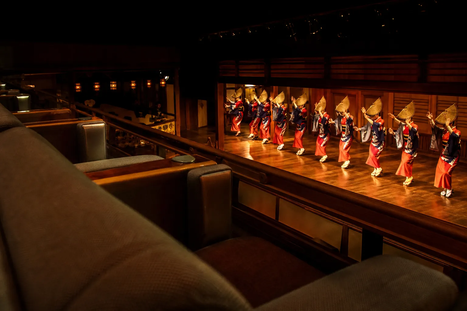 Awa Odori dancers performing on an indoor stage viewed from tiered reserved seating