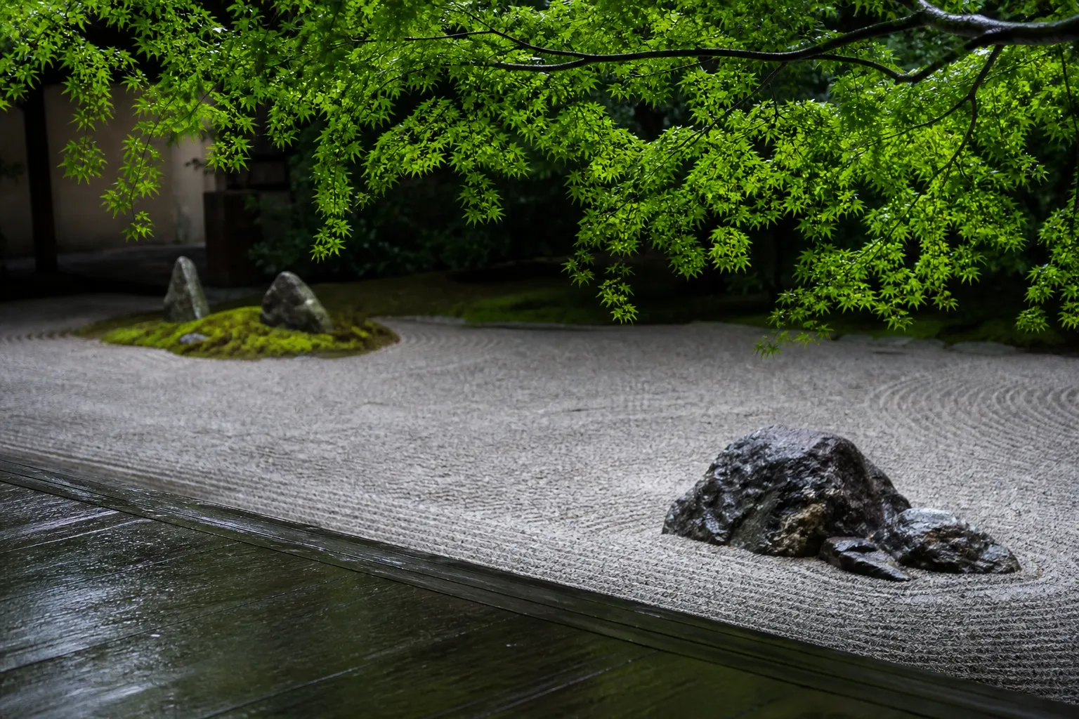 An empty Zen rock garden in Kyoto framed by lush, vibrant green maple leaves, highlighting the tranquil atmosphere available after the peak Golden Week travel period.