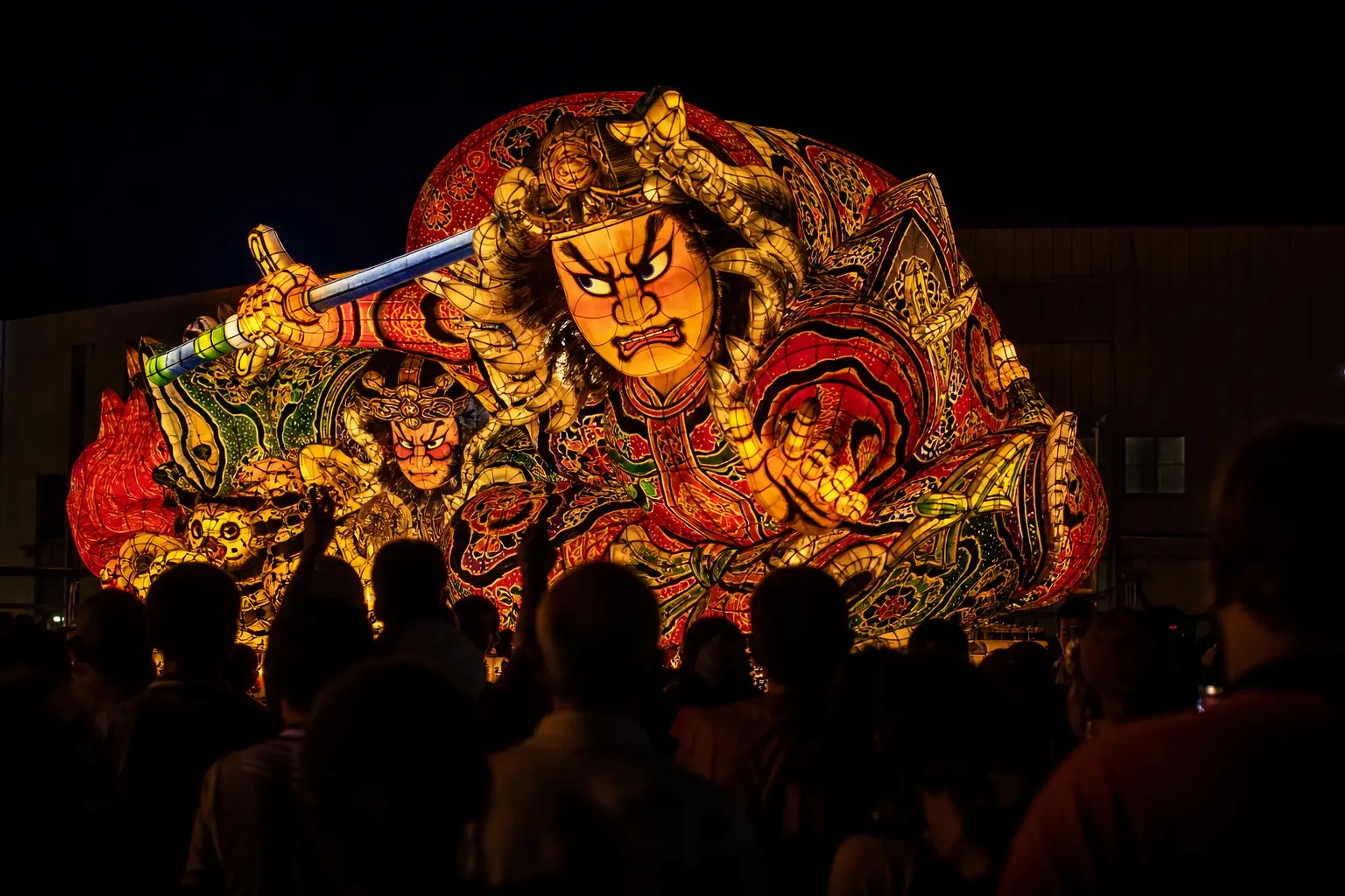 Illuminated Nebuta festival floats moving through an Aomori street at night