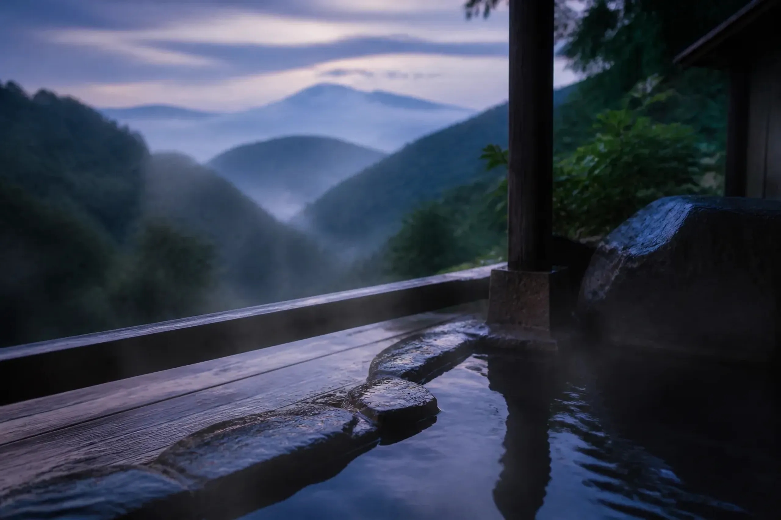 Steam rising from a Kyushu outdoor onsen with volcanic hills behind at dusk