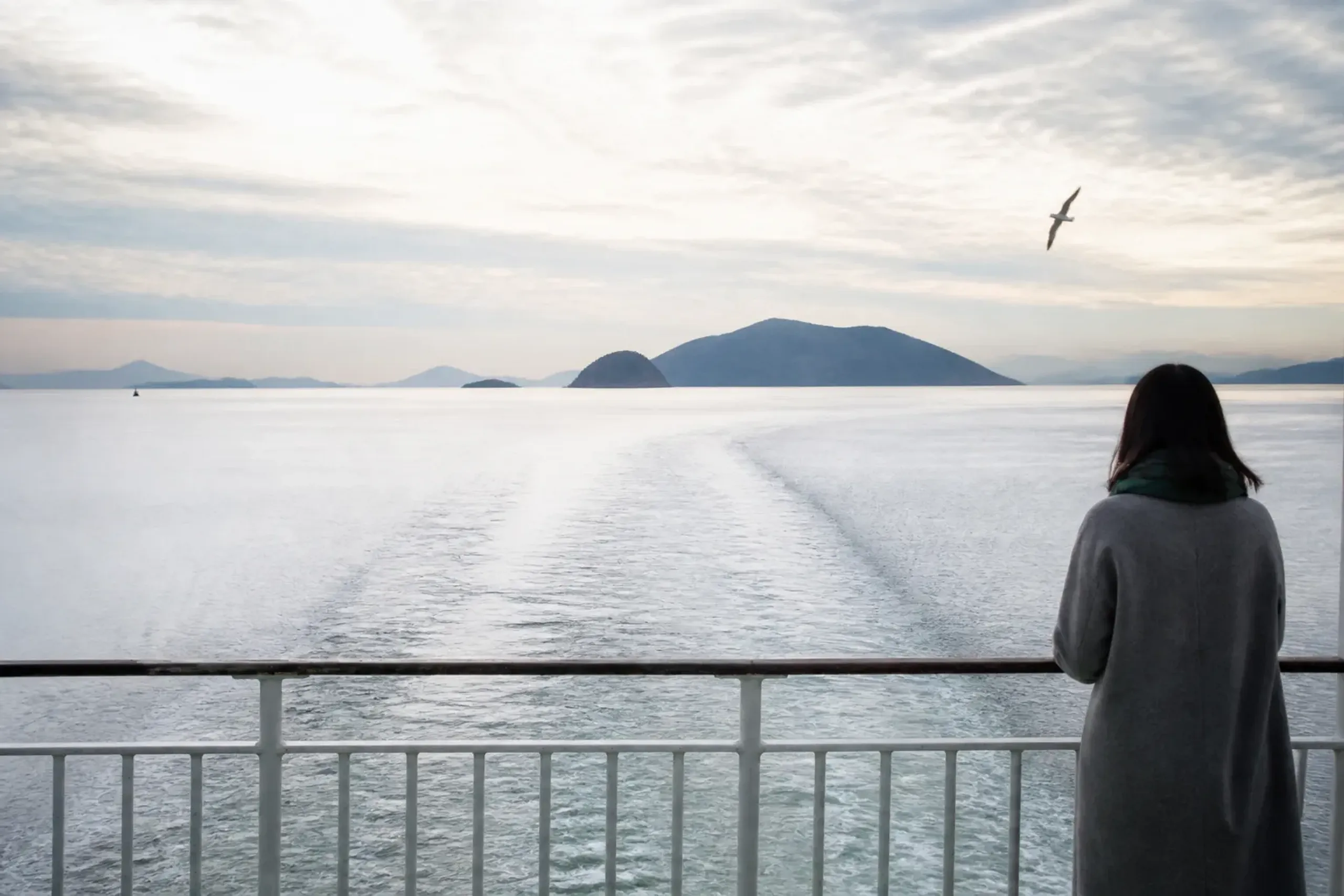 A ferry crossing calm Seto Inland Sea water toward green art islands