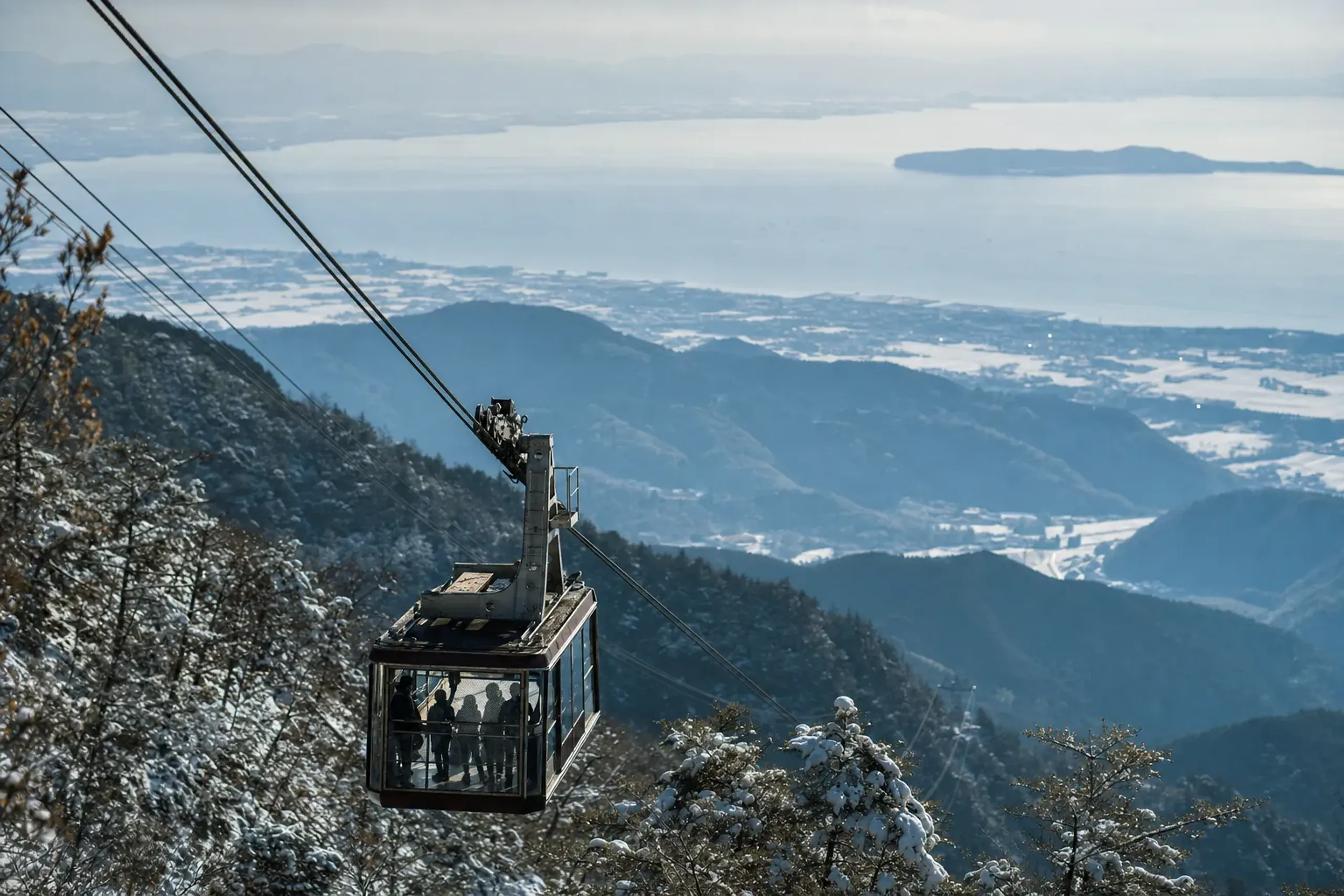 the fully glass-walled 121-passenger Biwako Valley ropeway cabin ascending above the pine-covered lower slopes toward Lake Biwa