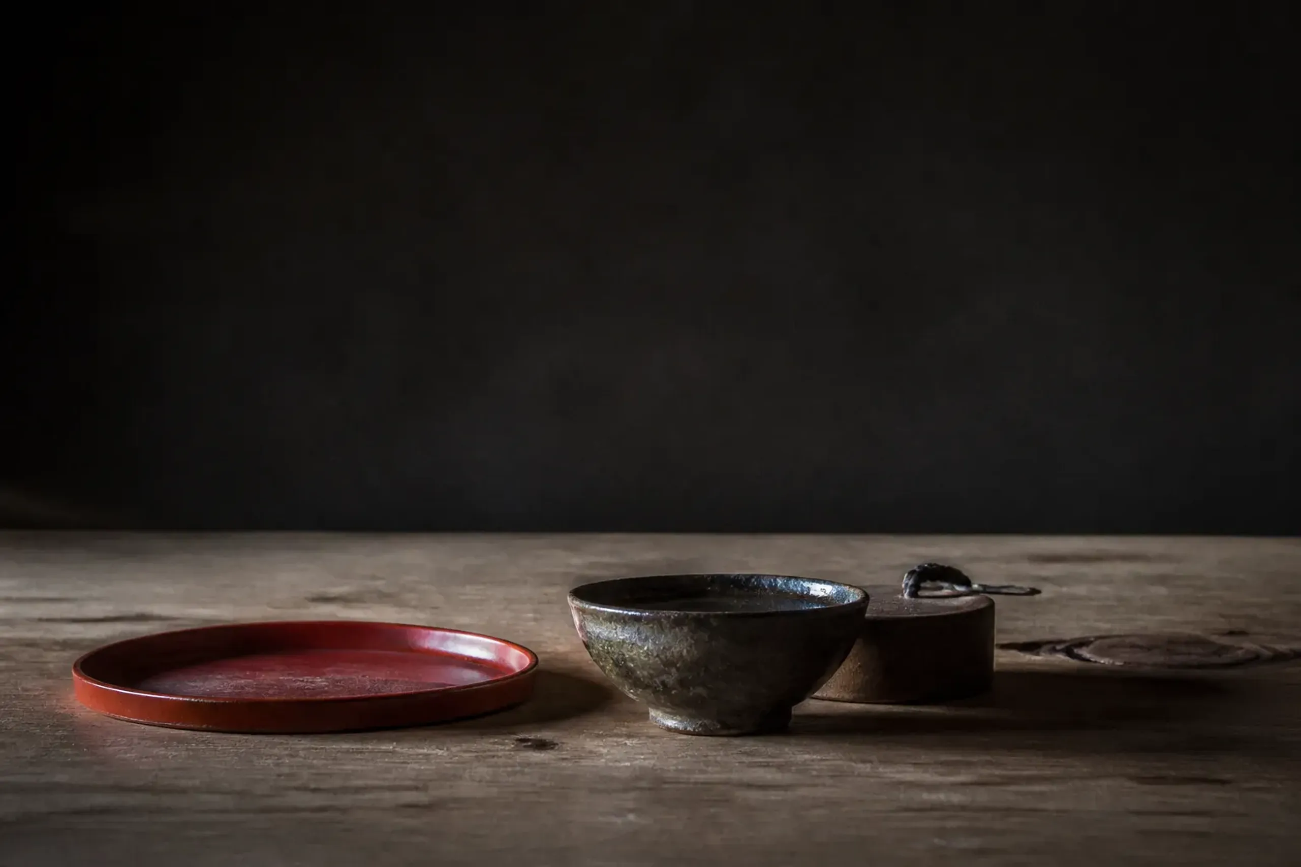 Person-free still life of Japanese kogei crafts including lacquerware and ceramics on a wooden table