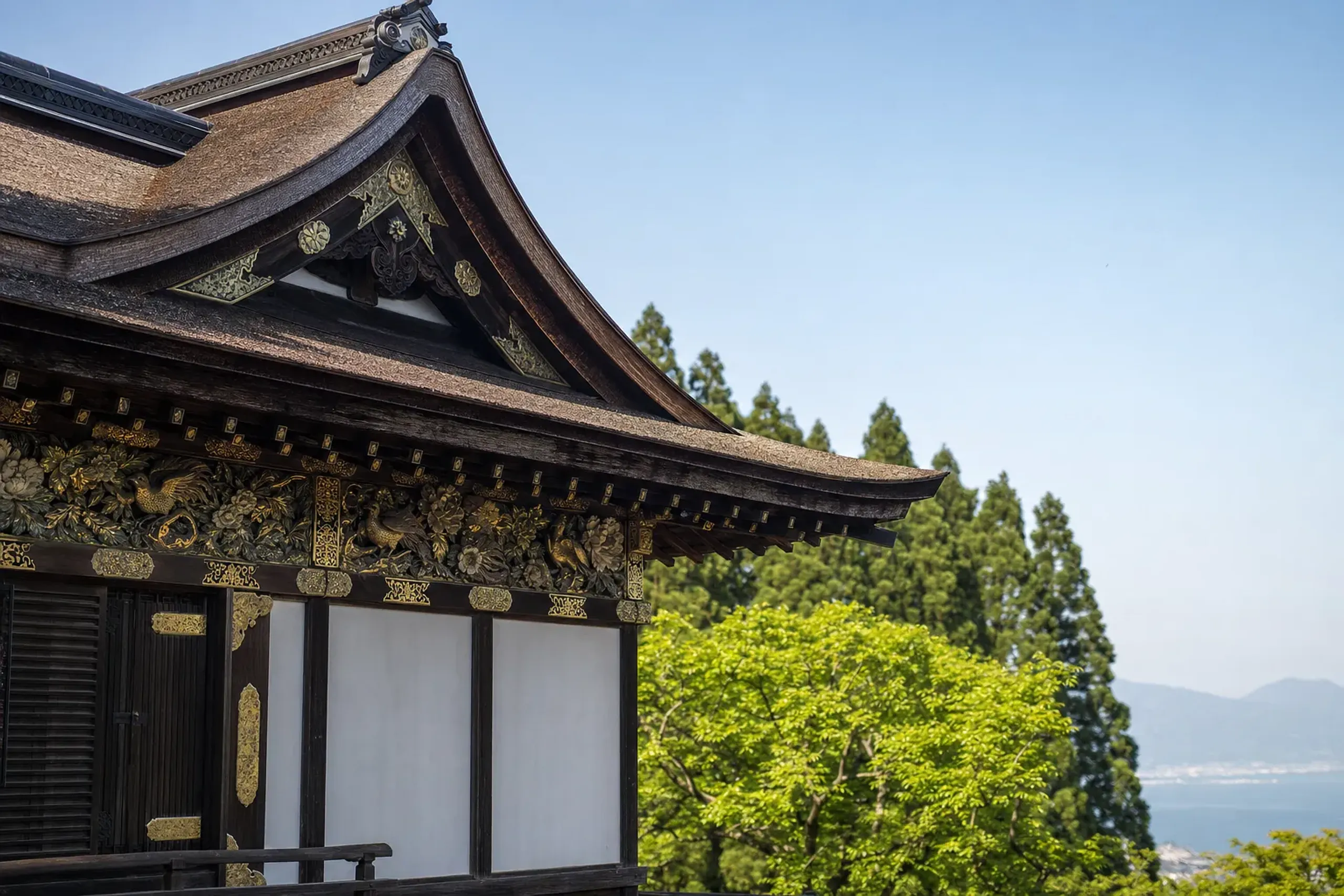 The cypress-bark irimoya roof and ornate carved transoms of the exterior of Tsukubusuma Shrine's main hall on Chikubushima