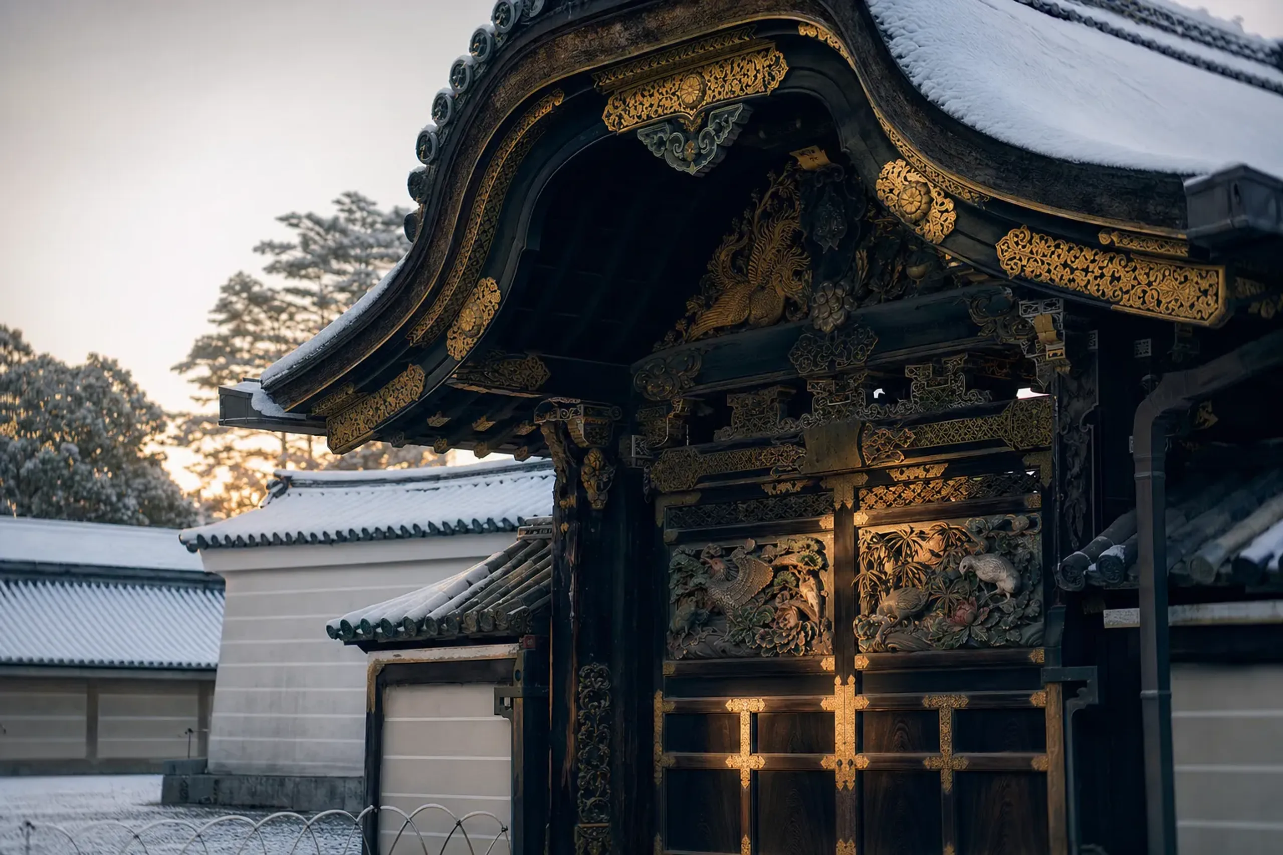 The black-lacquered Karamon Gate on Chikubushima with gold-plated fittings glowing and carved phoenix, pine, rabbit and peony motifs, seen in early soft light