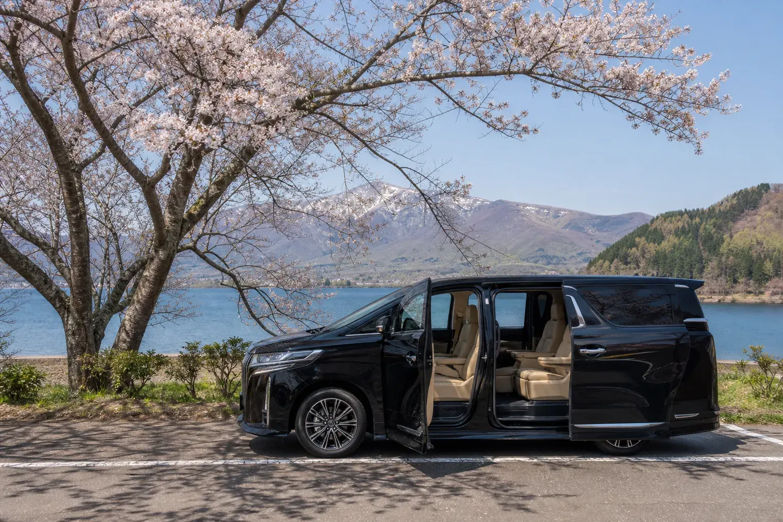 Black luxury minivan on a tree-lined Hokkaido road near Lake Shikotsu