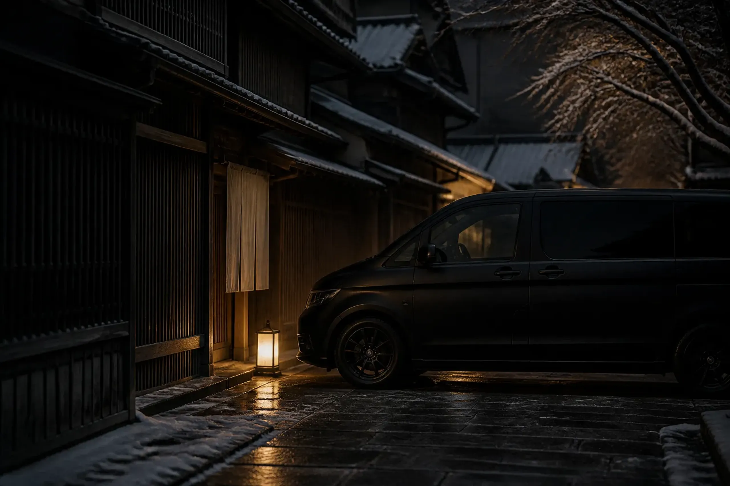 A discreet black luxury van parked at a quiet Japanese entrance at night for private arrival