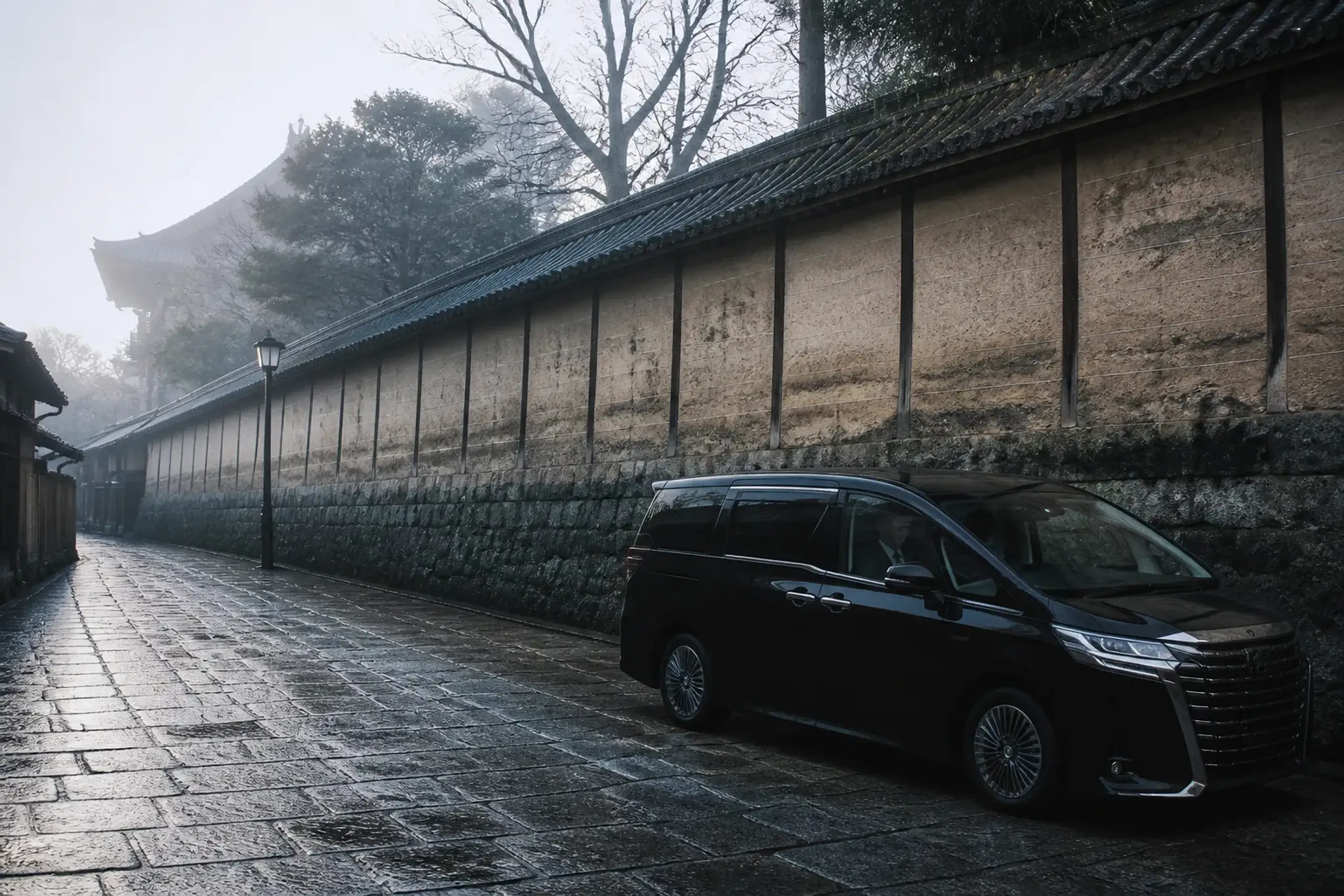 Luxury minivan waiting on a quiet Kyoto street near a temple wall