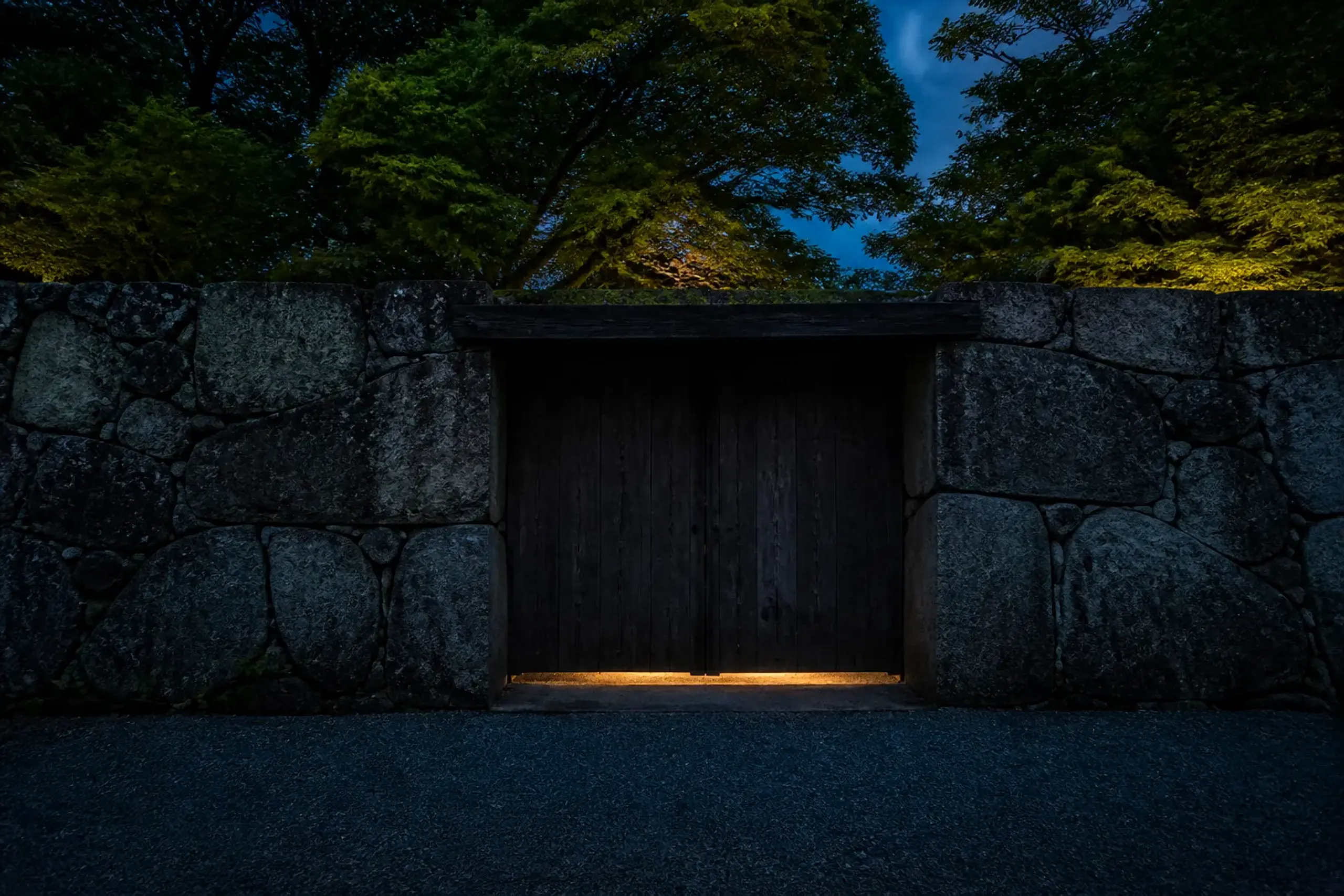 Closed dark-timber private estate gate in Japan with stone wall and no signage or people