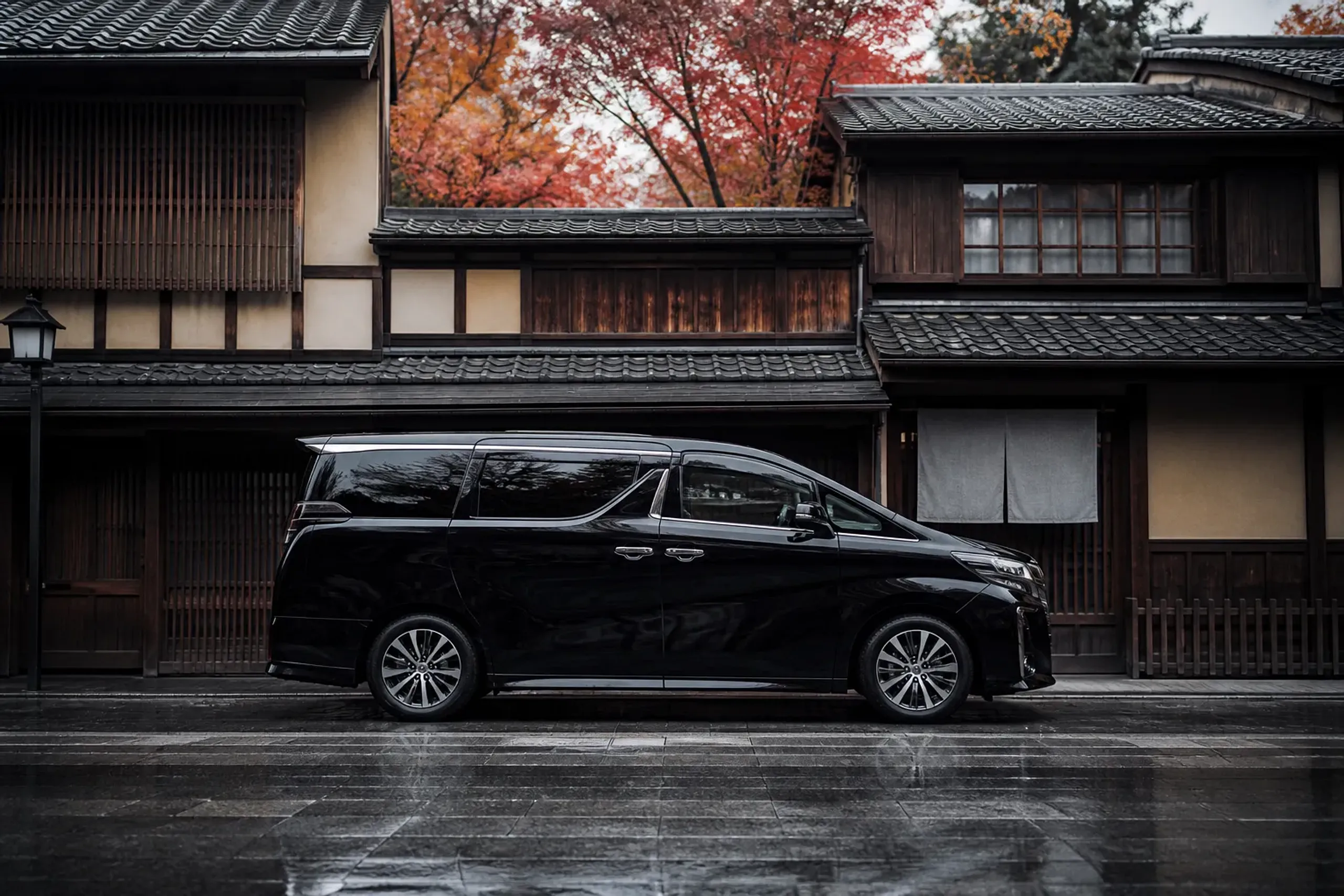Black luxury minivan parked on a quiet empty Japanese street in early morning light