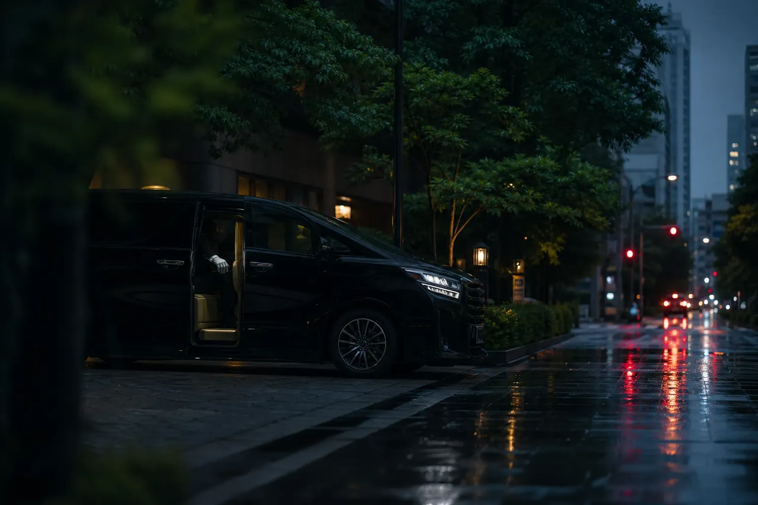 Black chauffeured Toyota Alphard on a wet Tokyo street at night with city reflections