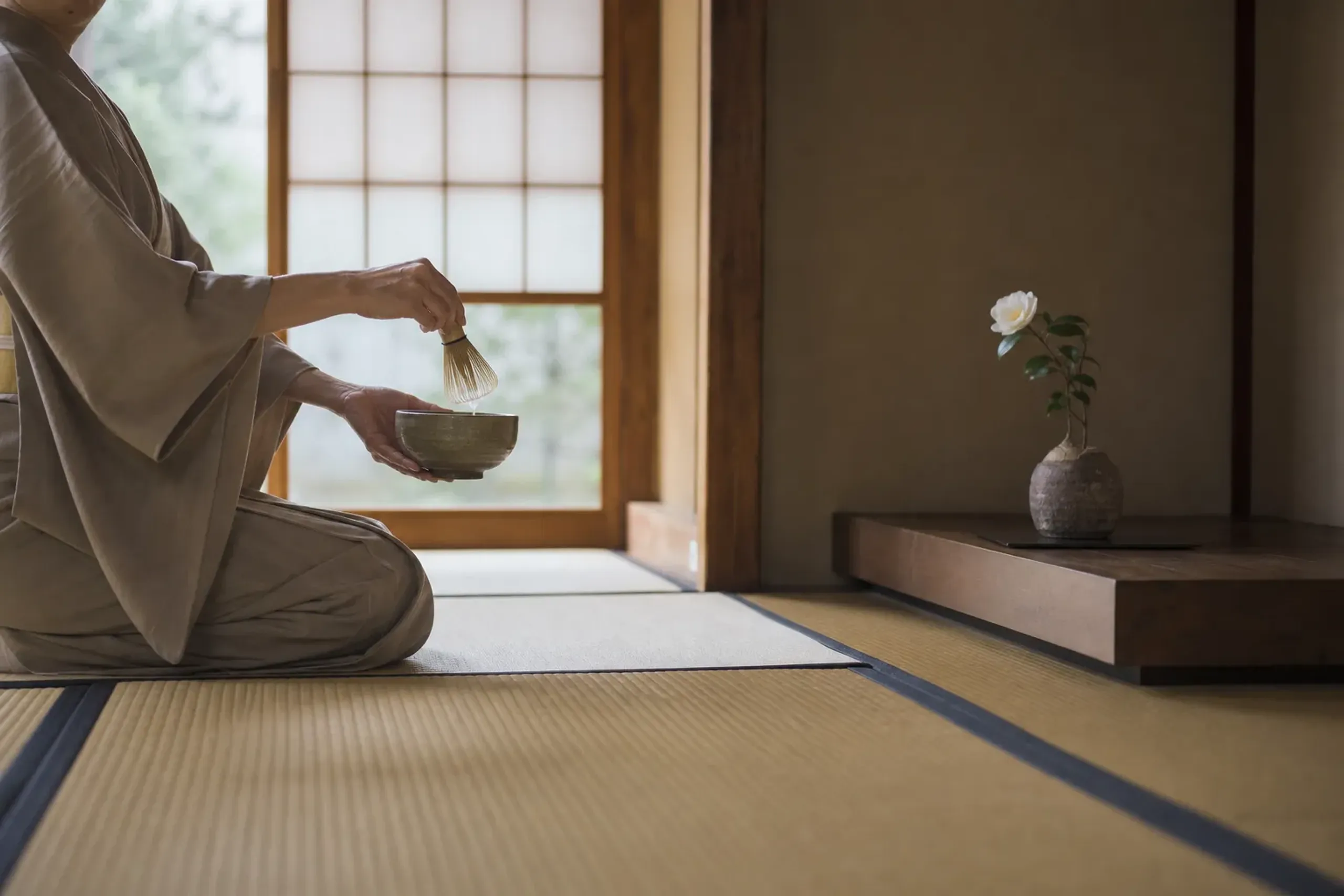 Tea master in kimono preparing matcha in a quiet tatami room with soft natural light