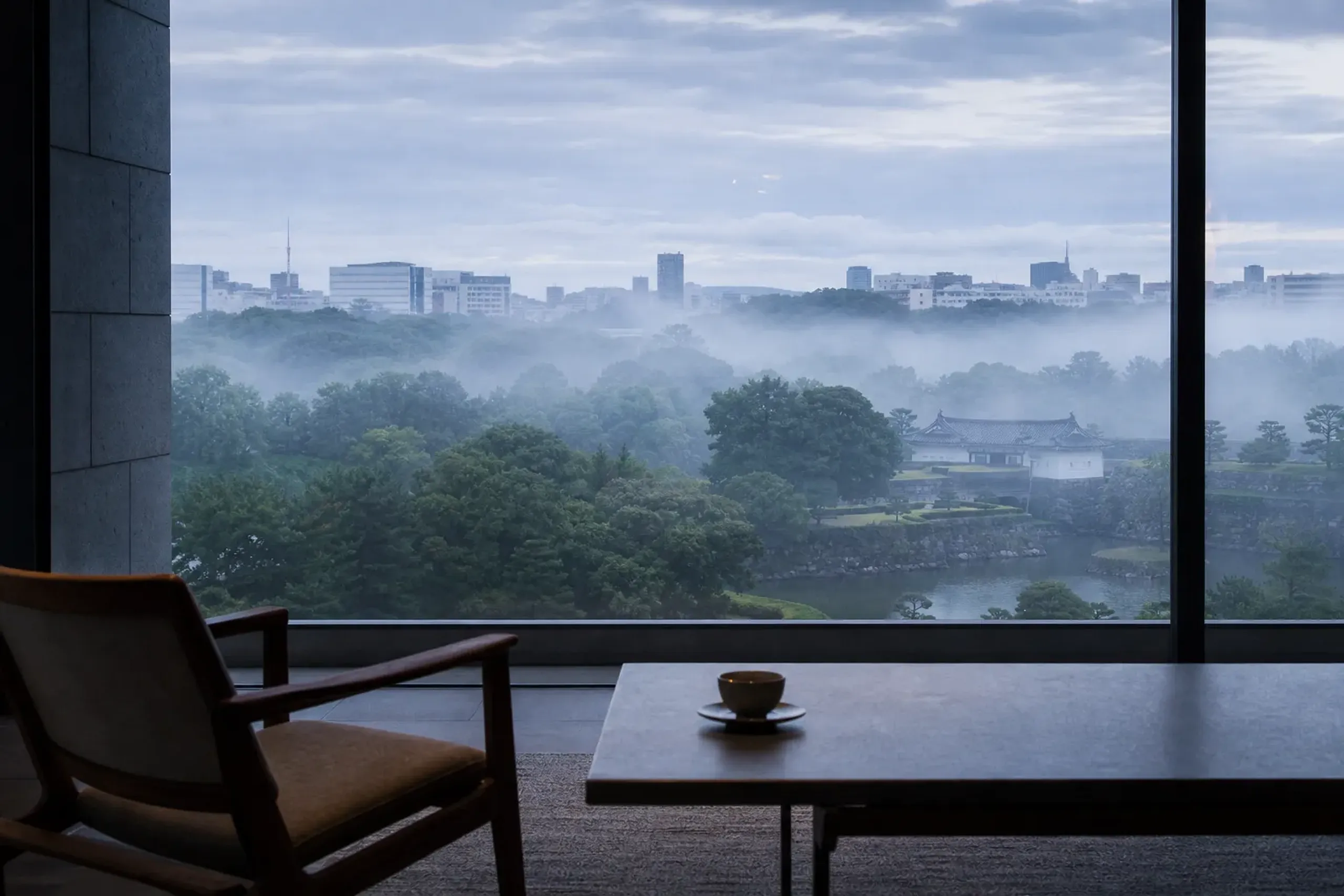 Imperial Palace gardens viewed through a floor-to-ceiling window of a modern Tokyo hotel