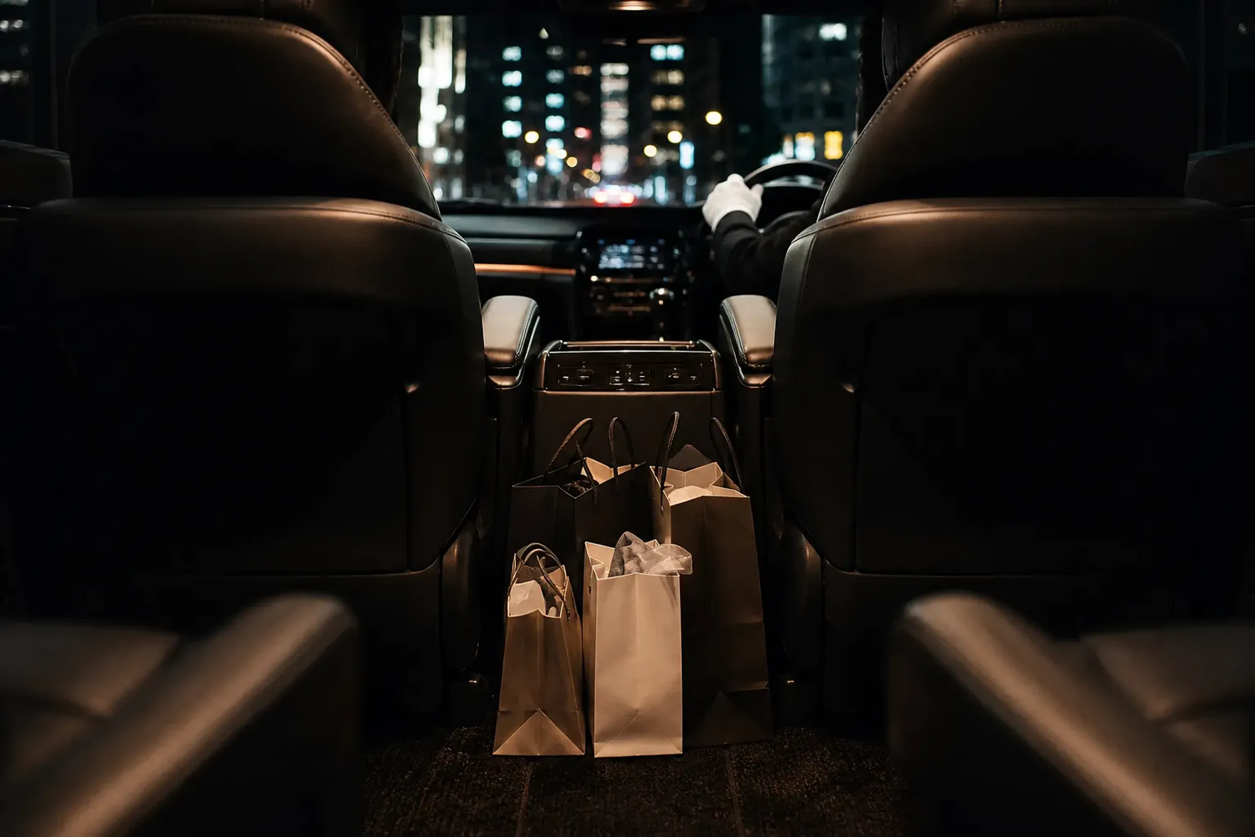 Depachika shopping bags inside a luxury minivan during an evening city drive