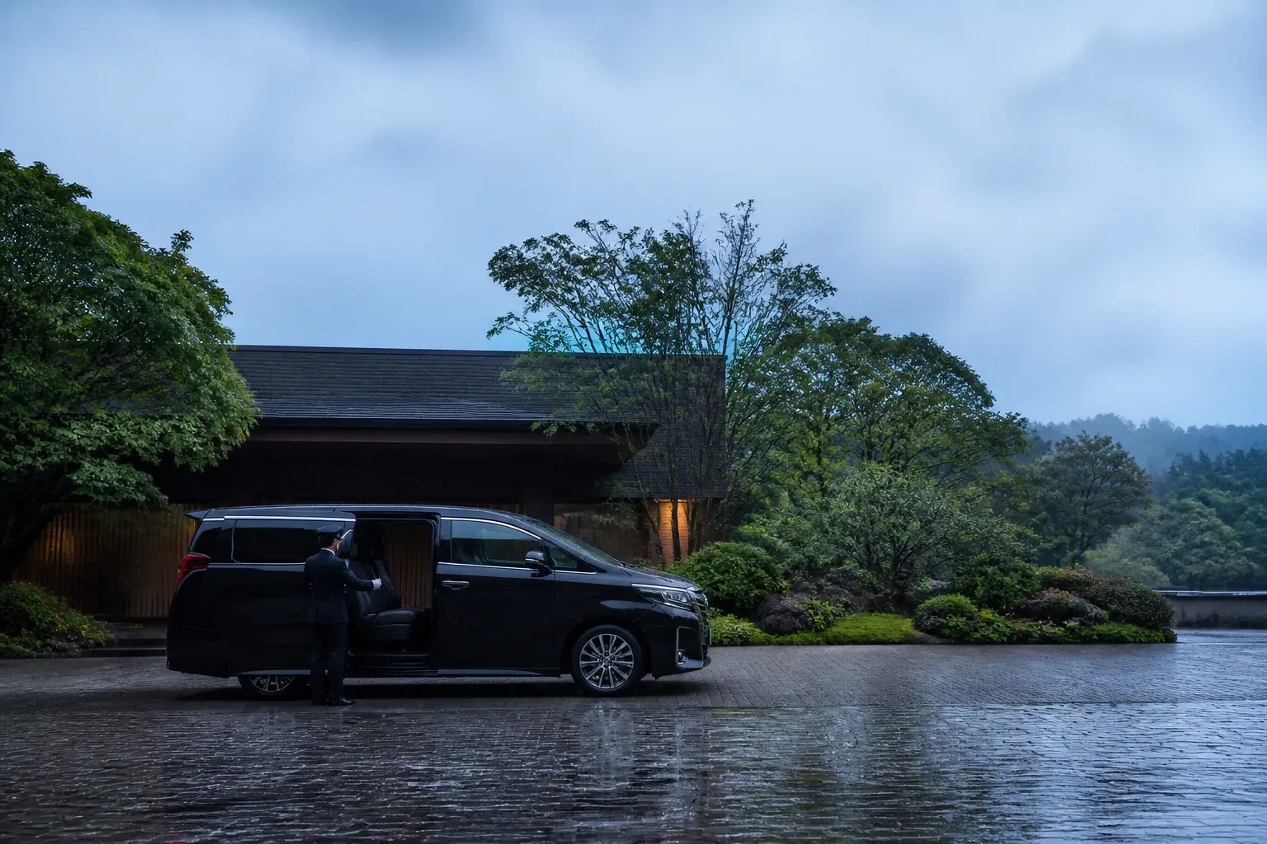 Chauffeured luxury minivan at a Tokyo hotel entrance with door opened for guests