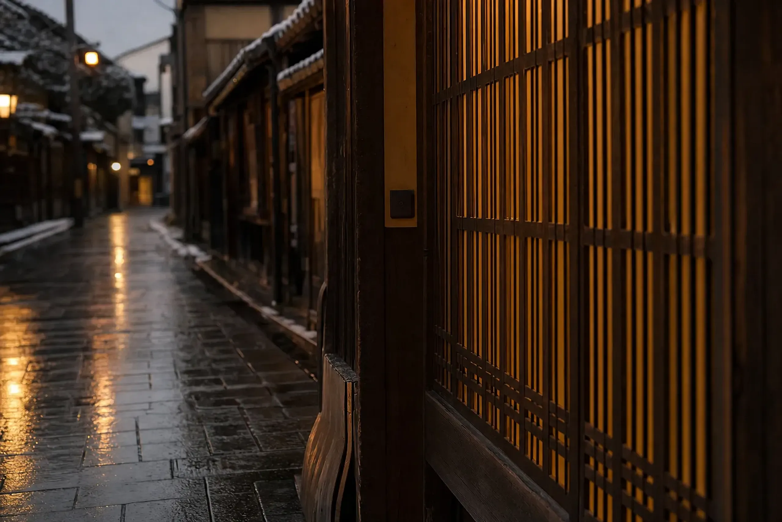 The amber-glowing lower latticework of a machiya townhouse on Hanami-koji in Gion Kōbu after dark