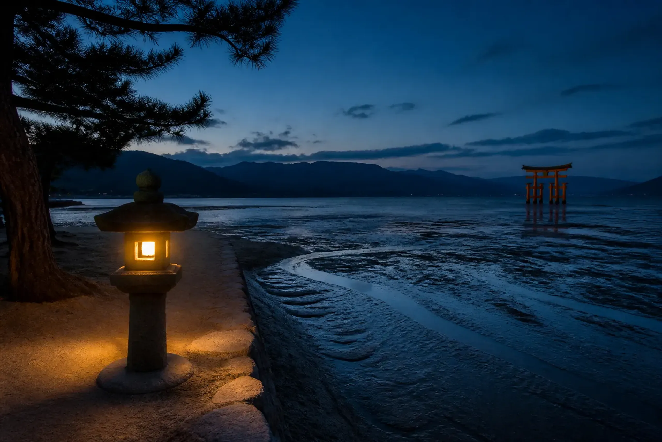 Quiet evening shoreline on Miyajima with the torii of Itsukushima Shrine in the distance