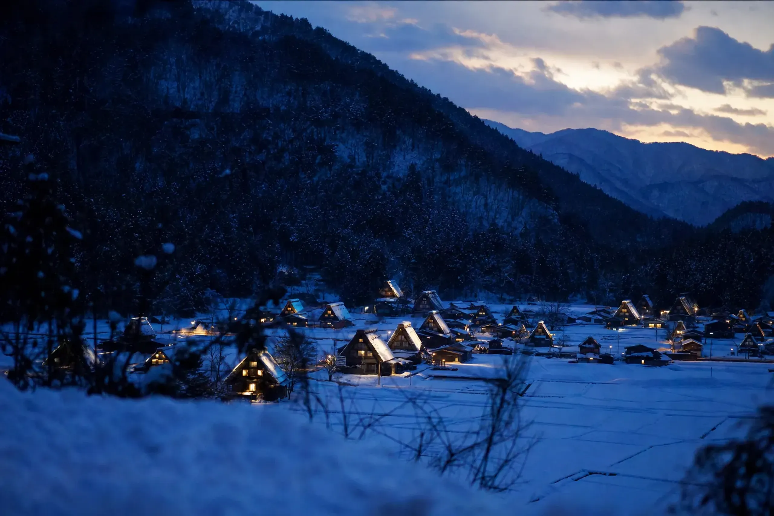 the illuminated gassho-zukuri farmhouses of Shirakawa-go glowing against deep snow during the evening winter light-up