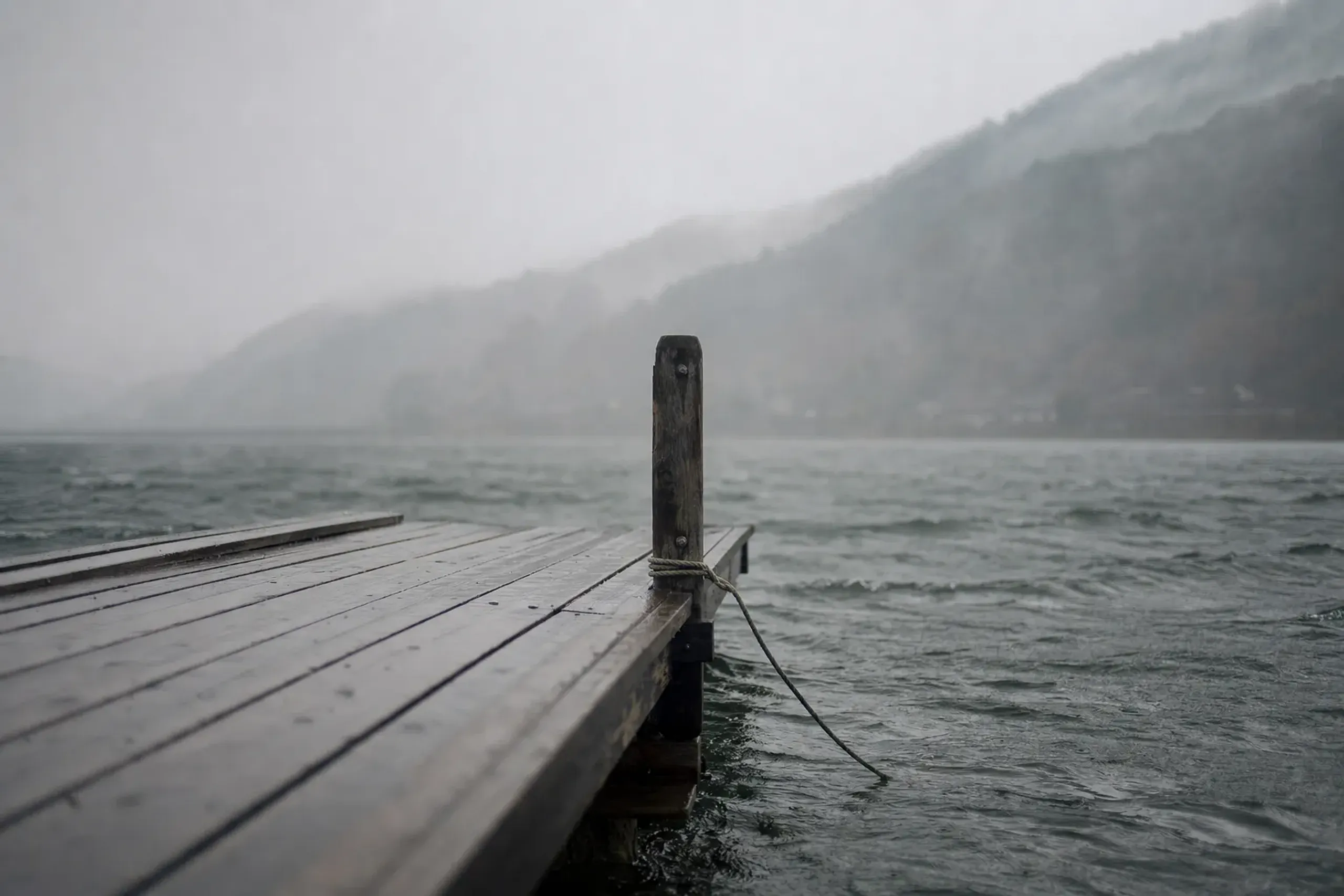 the wooden boat dock at the south end of Togetsukyō Bridge in Arashiyama, empty and waiting under grey, windy river conditions