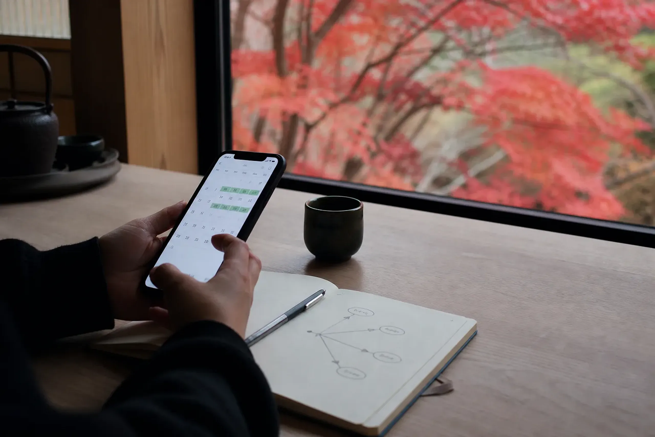 Traveler viewing a reservation calendar on a smartphone beside a notebook