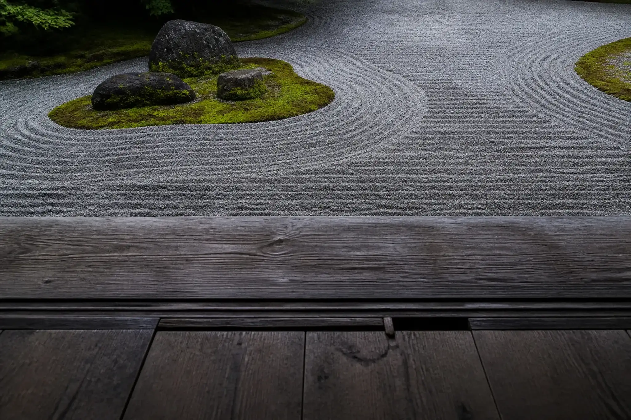 Zen garden with raked gravel, mossy stones, and a wooden veranda edge in Kyoto