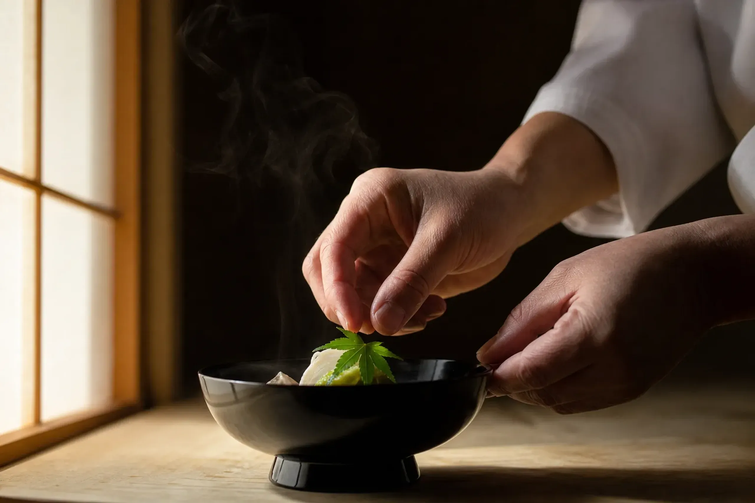Chef’s hands plating a kaiseki dish on lacquerware at a wooden counter in Kyoto