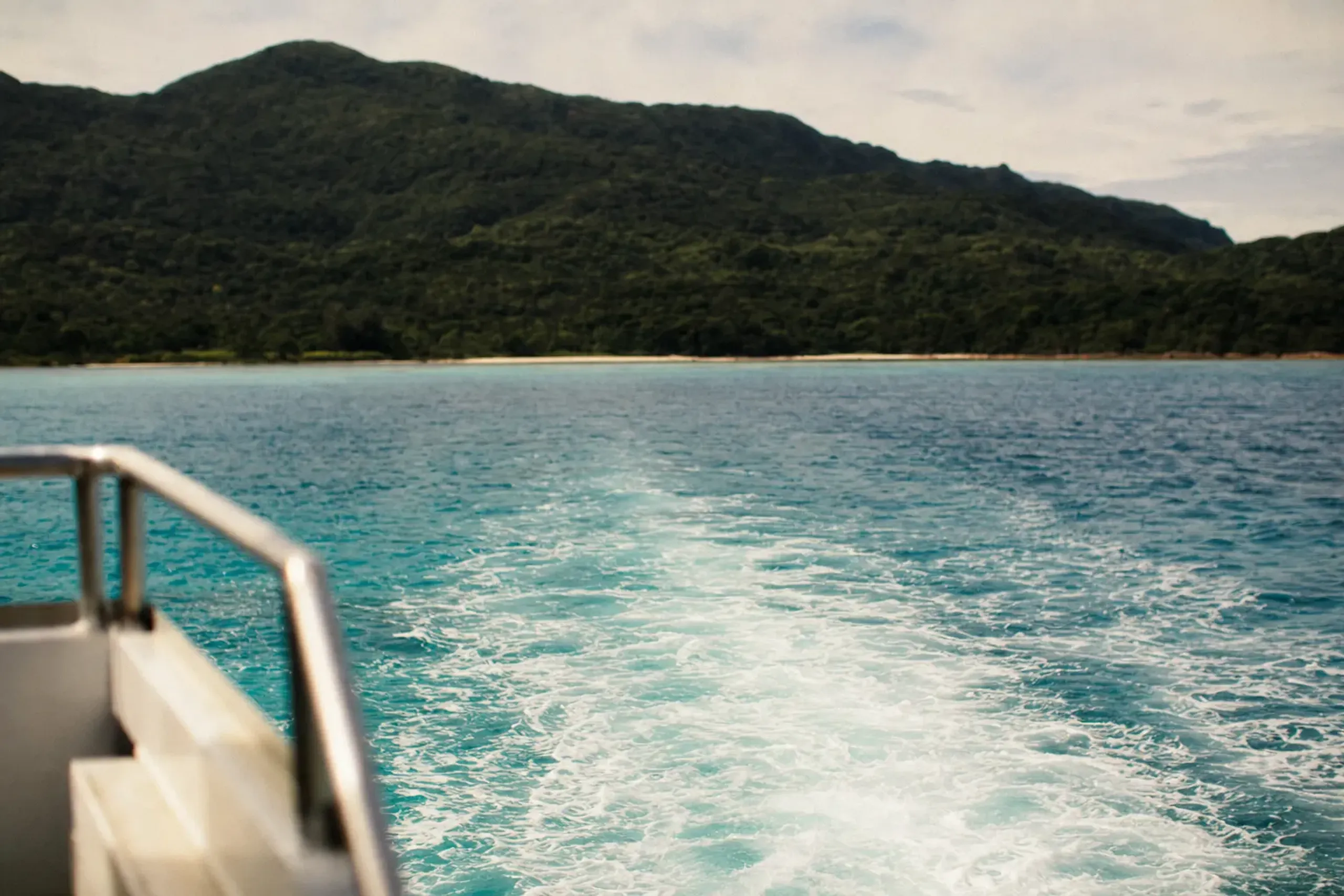 a passenger ferry crossing the sea from Ishigaki toward the forested coastline of Iriomote Island