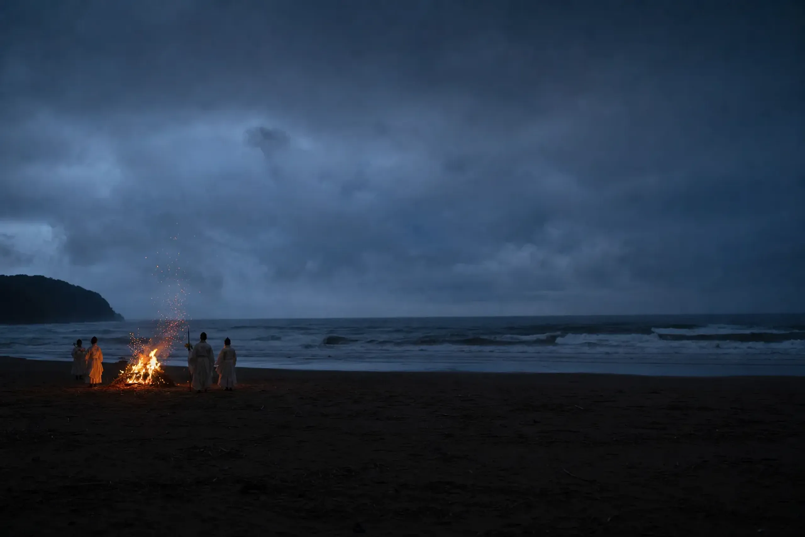 The sacred bonfire of the Kamimukae Shinji welcoming rite blazing against the dark breaking waves at Inasa Beach near Izumo Taisha at dusk