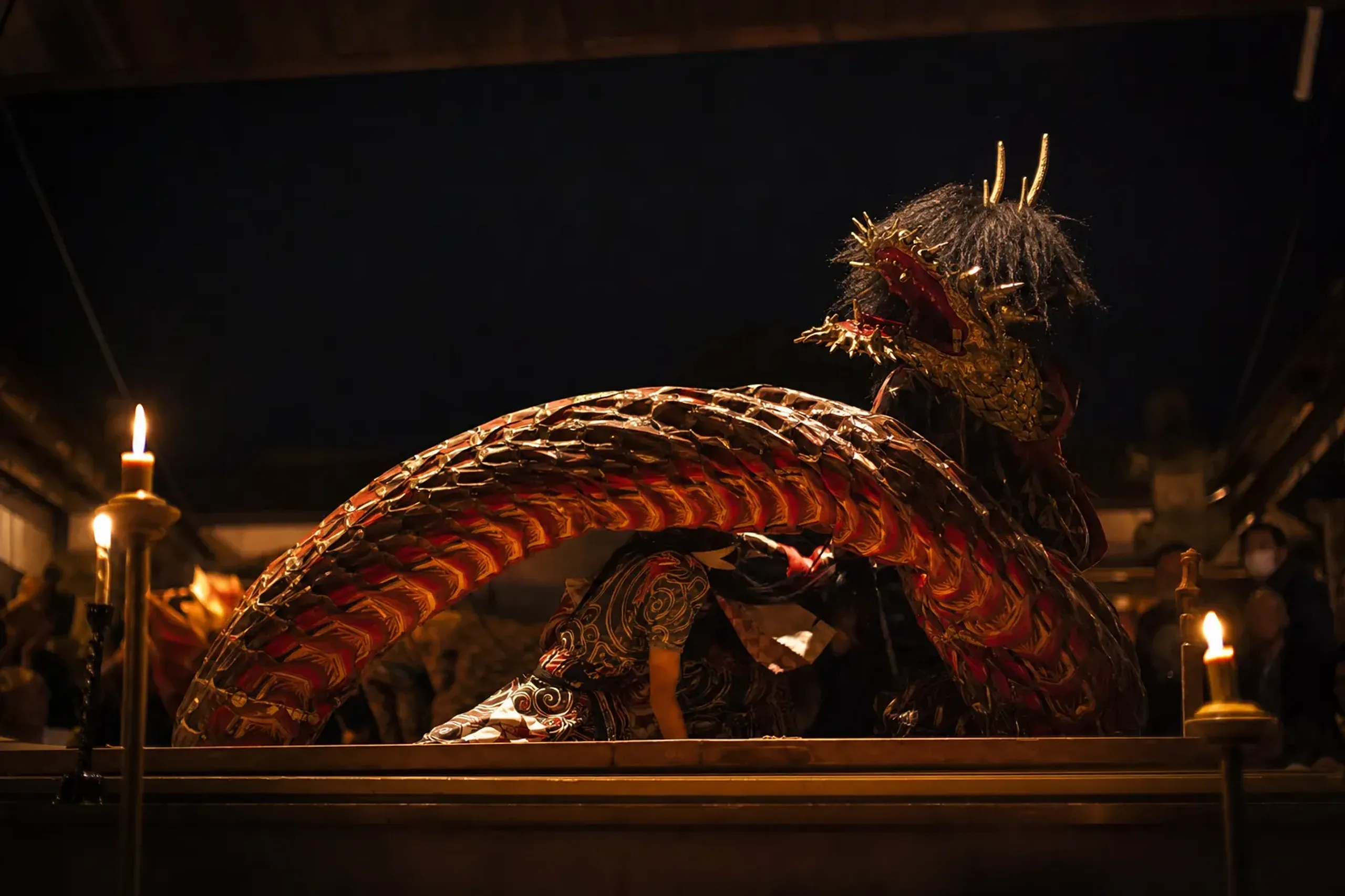 An evening Izumo Kagura performance featuring a dragon-serpent deity costume in dynamic motion