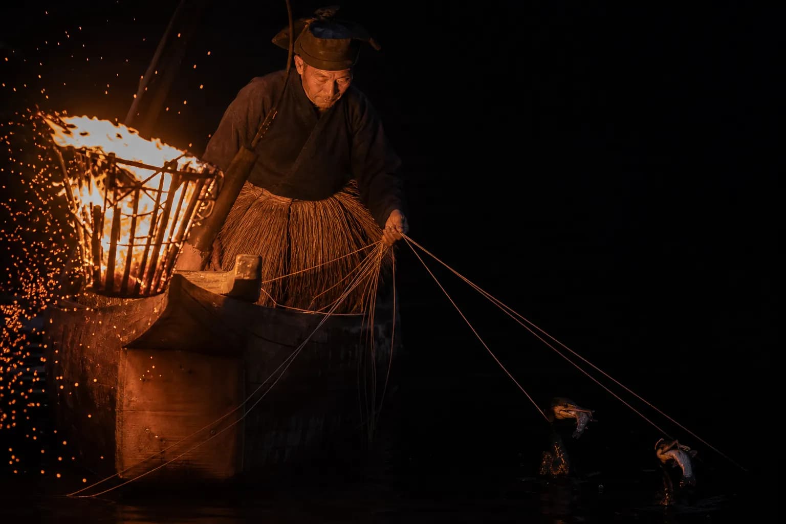 Cormorant fisherman guiding trained birds by torchlight on the Nagara River in Gifu at night