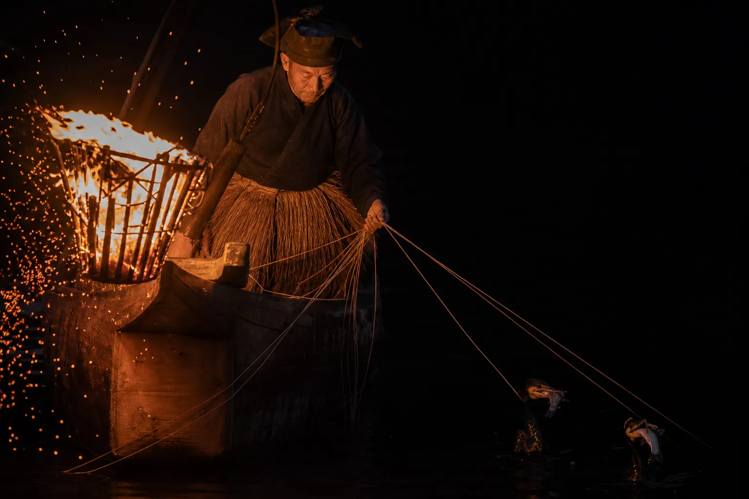 Cormorant fisherman guiding trained birds by torchlight on the Nagara River in Gifu at night
