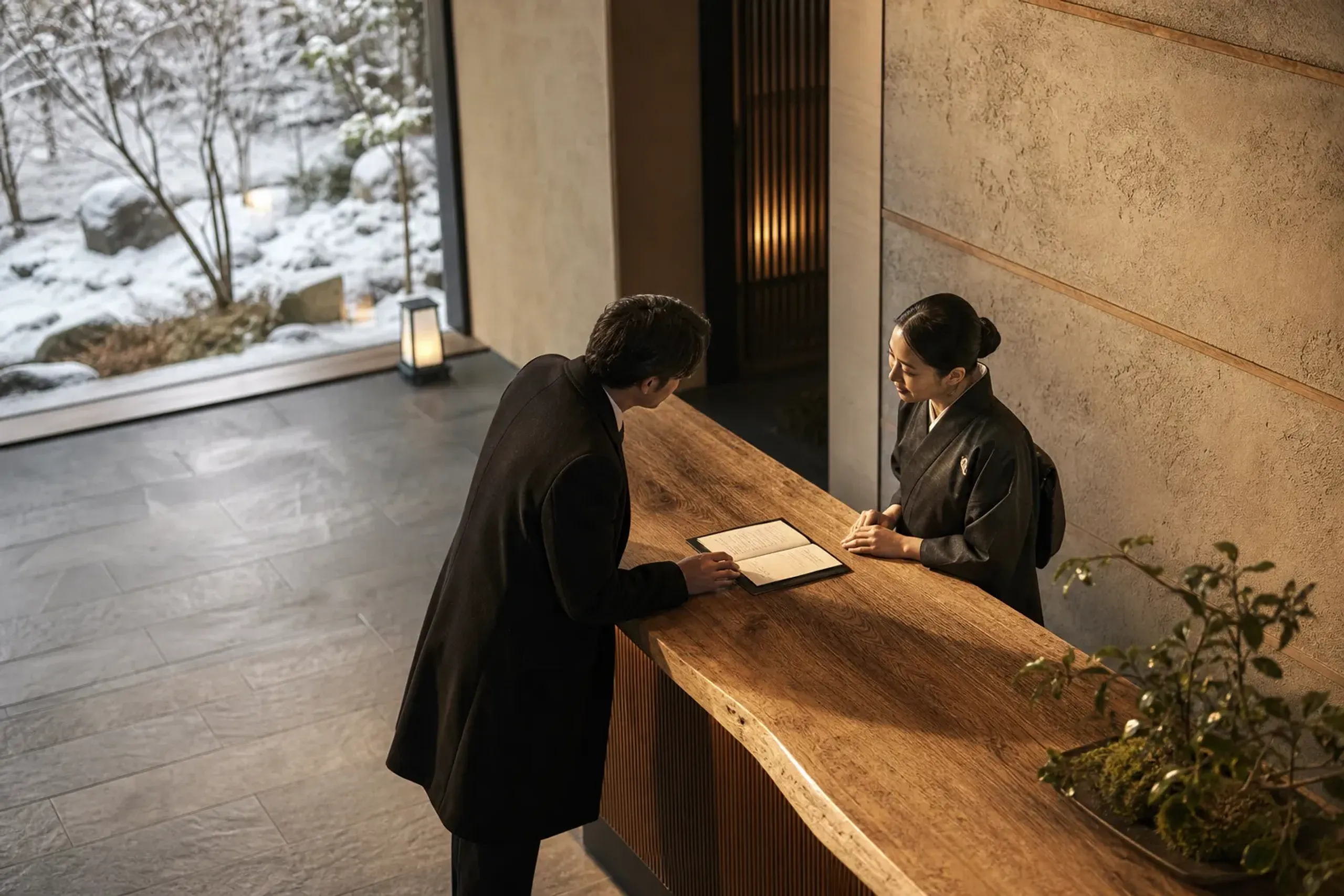 Guest speaking with a hotel concierge in Japan with a reservation notebook on the desk