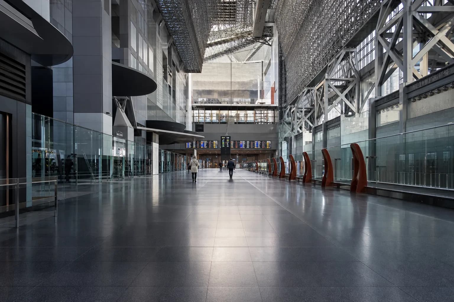 Quiet Kyoto Station corridor with departure boards visible in the distance
