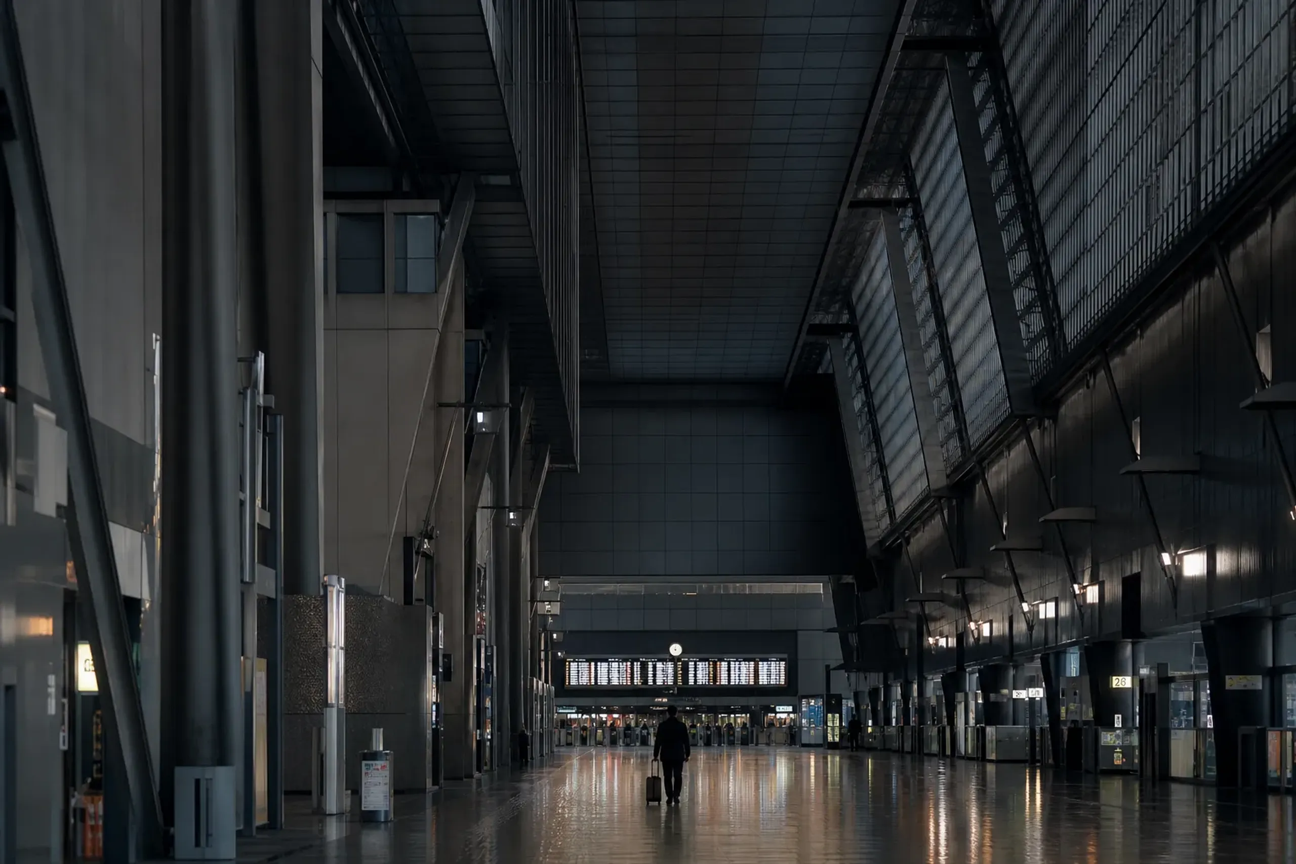 Quiet Kyoto Station corridor with departure boards visible in the distance