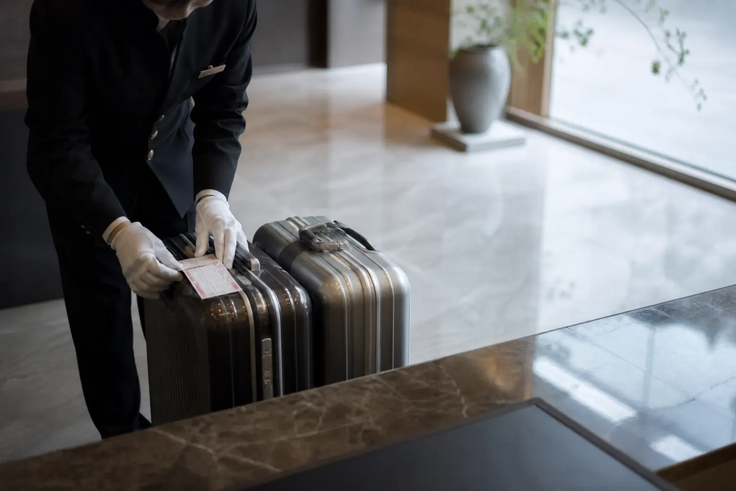 Hotel staff attaching a delivery slip to suitcases for luggage forwarding between cities in Japan