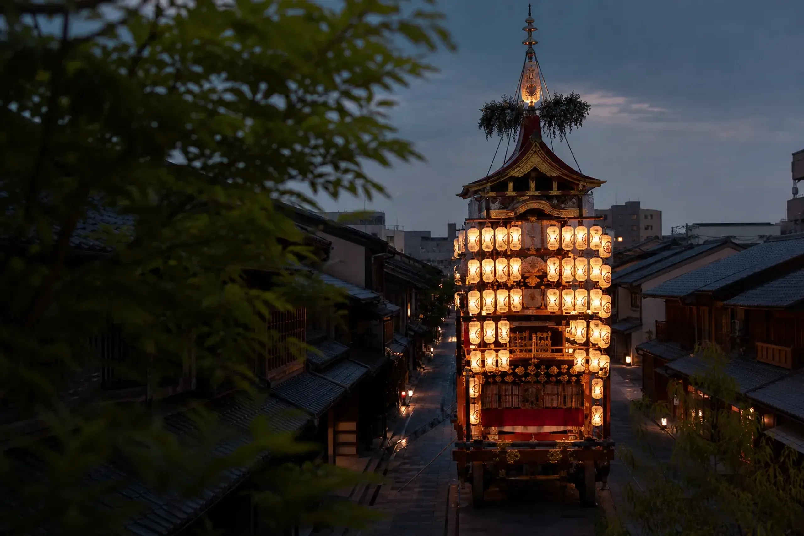 Illuminated Gion Matsuri festival float with lanterns on a closed Kyoto street at dusk