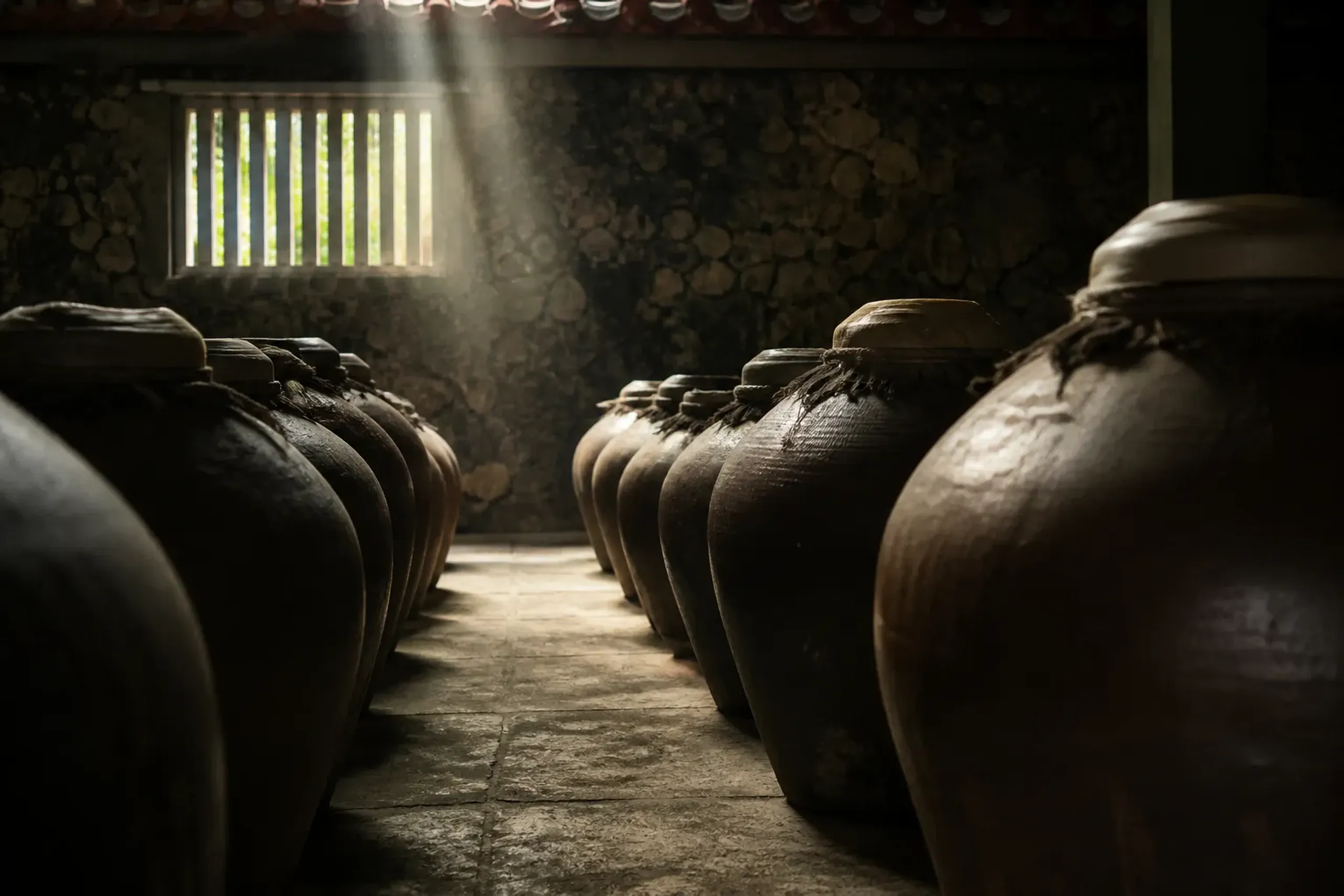 Awamori aging area in Okinawa with clay pots and barrels