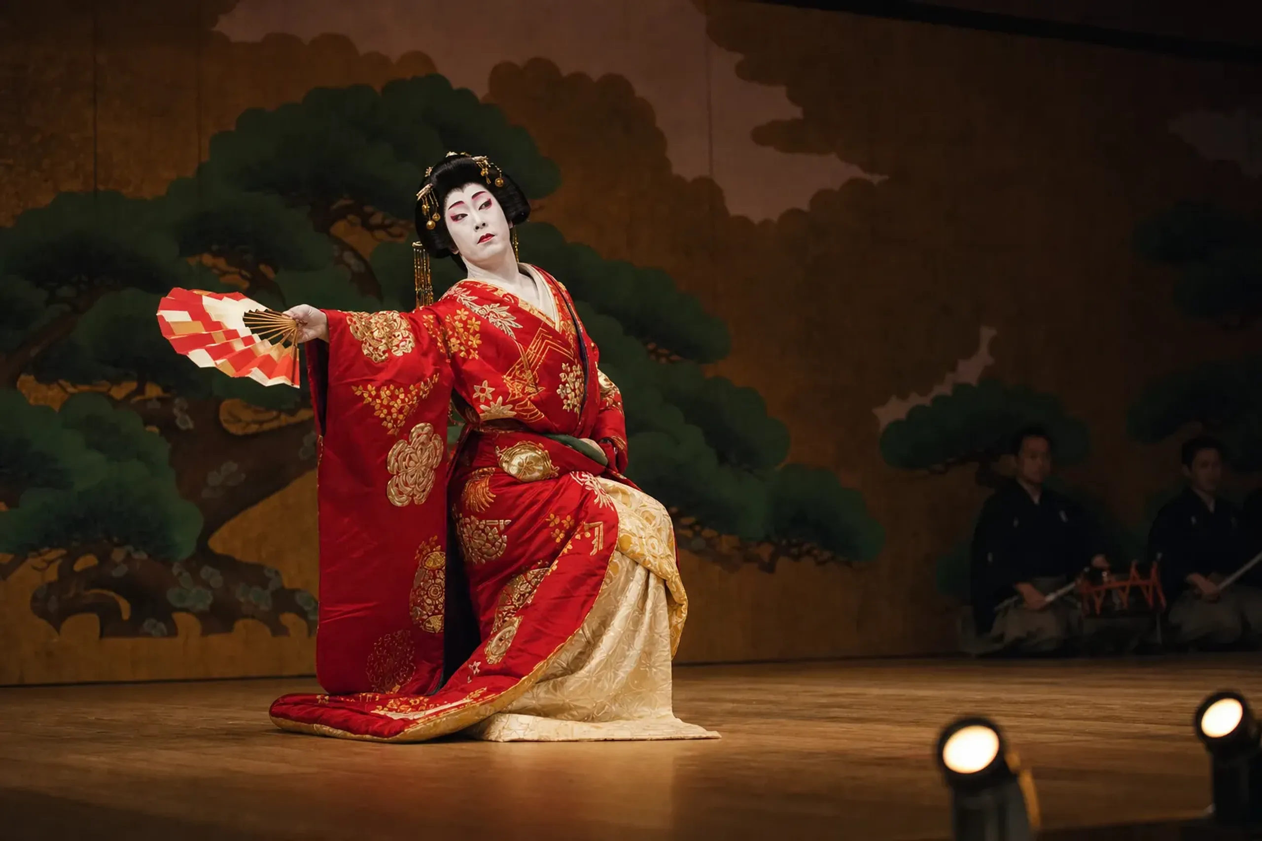 A stylised kabuki dance scene on the Kabuki-za stage with an actor mid-pose in ornate costume against painted scenery