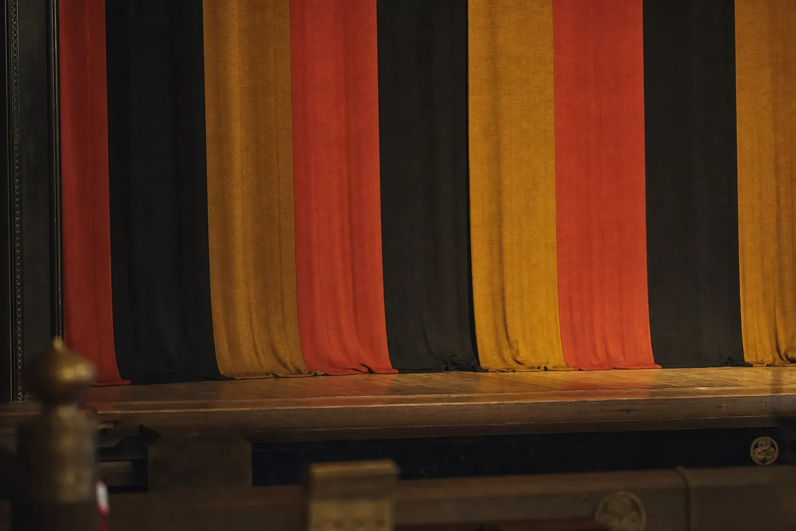 A tiered vermilion-and-gold striped Kabukiza stage curtain (jōshiki-maku) closed between program segments