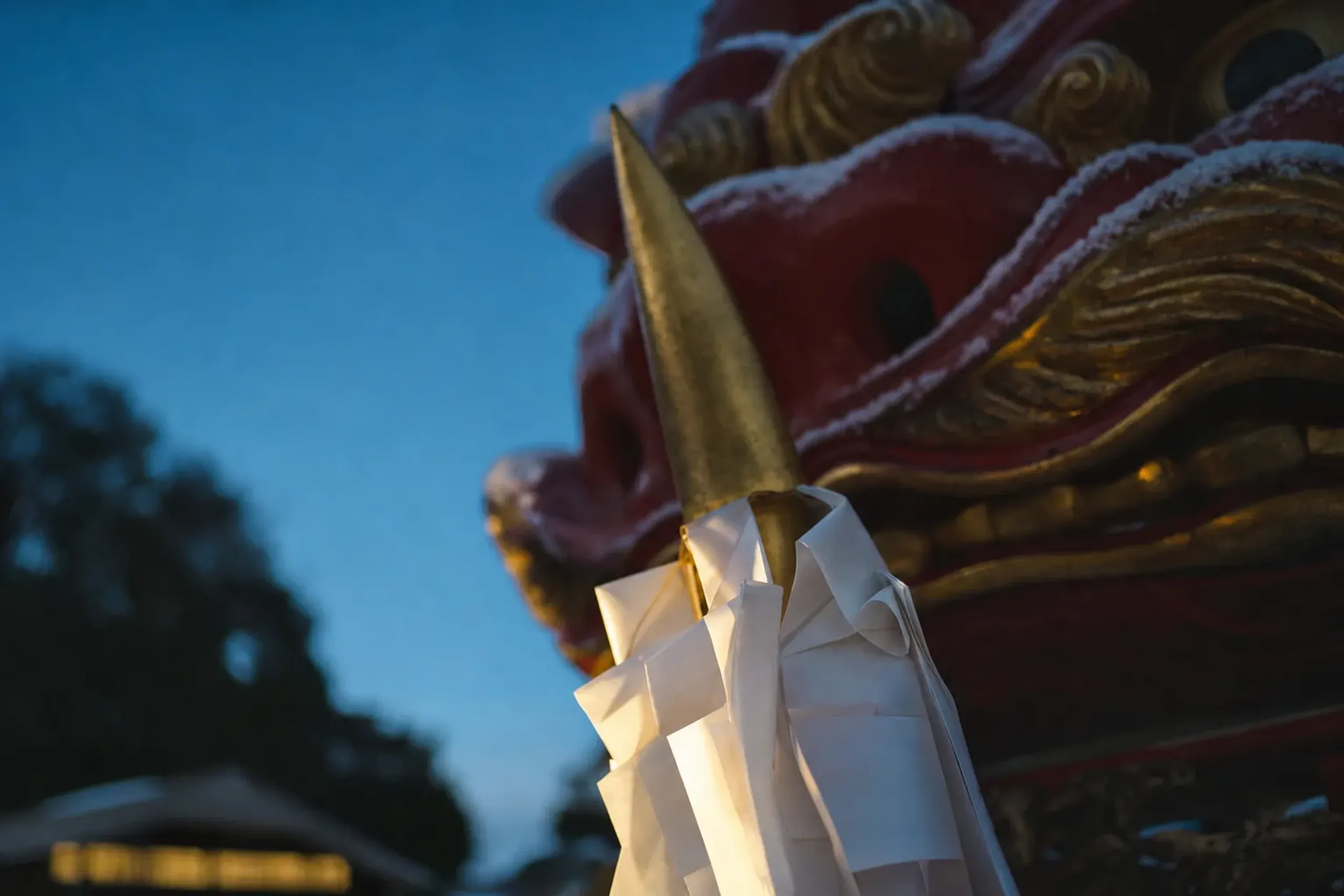 The freshly made paper streamer placed behind the horn atop Katanamachi's Red Lion (Aka-jishi) hikiyama float, a delicate purified paper element against the monumental golden lion head