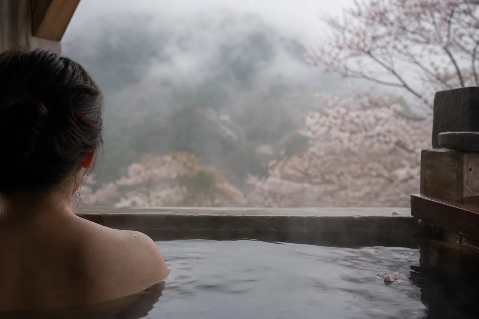 An exclusive private hot spring bath looking out over colorful autumn forest leaves