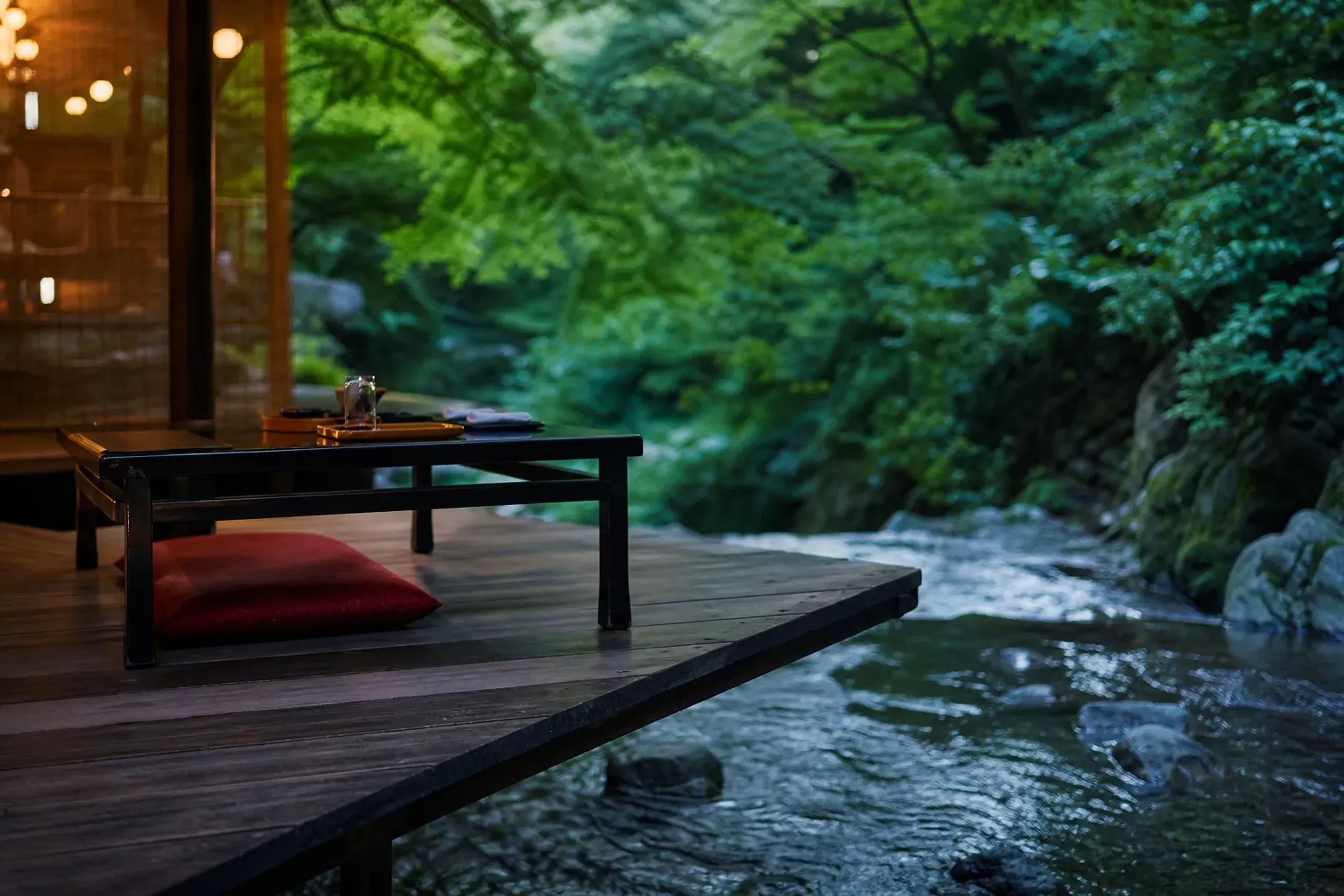 Wooden kawadoko dining platform over the Kibune River surrounded by green maples in summer