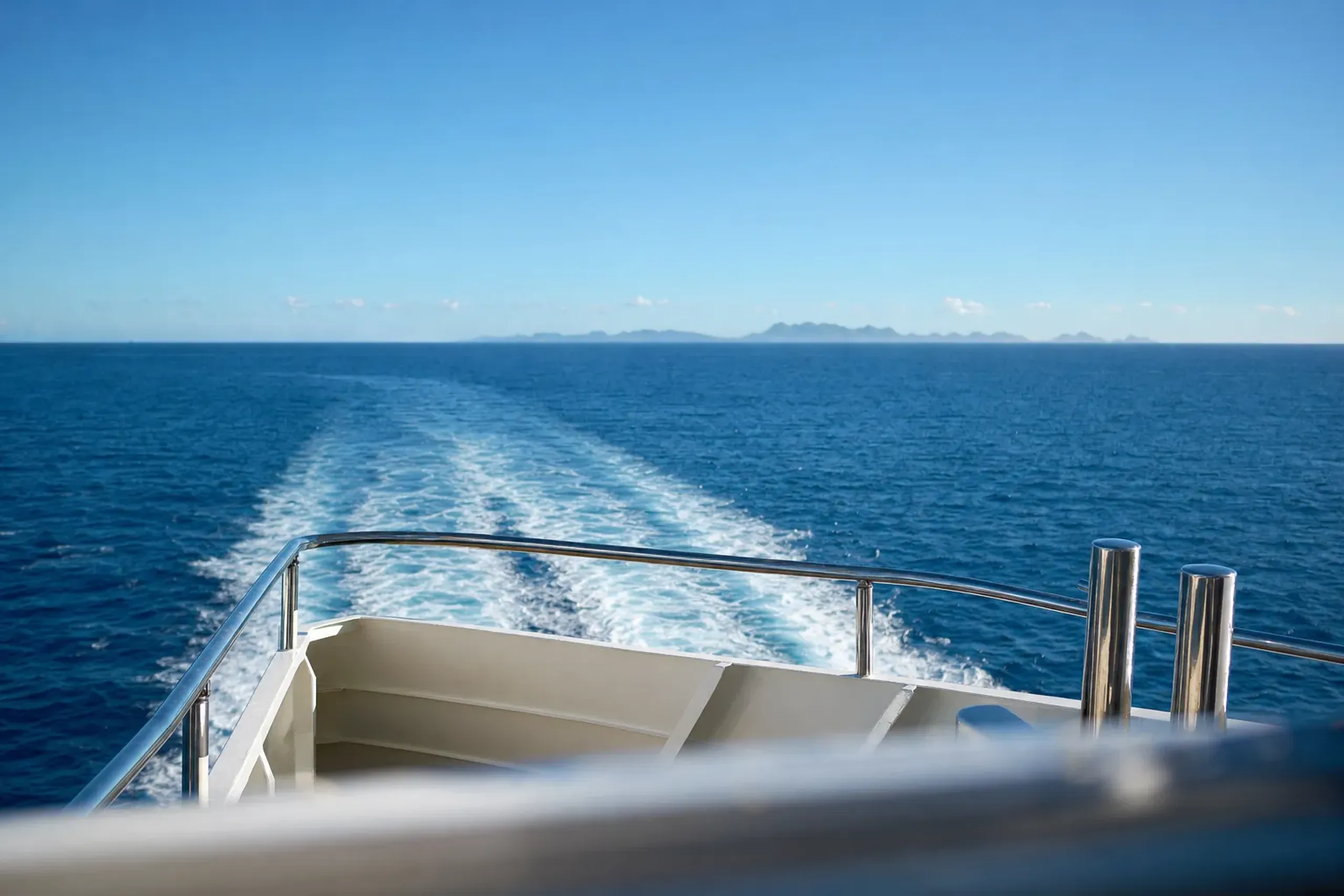 a white high-speed passenger ferry crossing the deep blue open water between Naha and the Kerama Islands under a clear sky